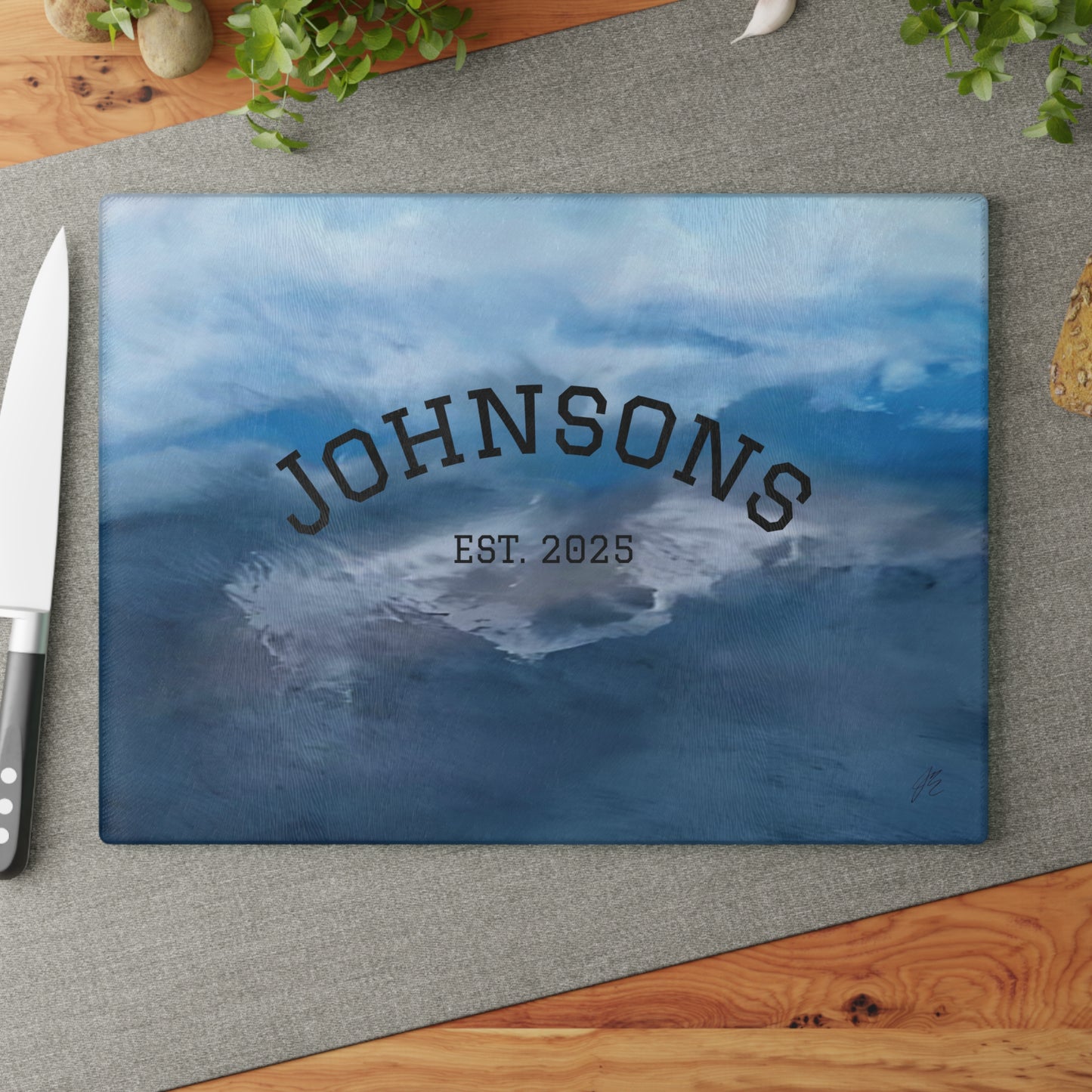 Personalized cutting board with 'JOHNSONS EST. 2025' text on a wooden surface.