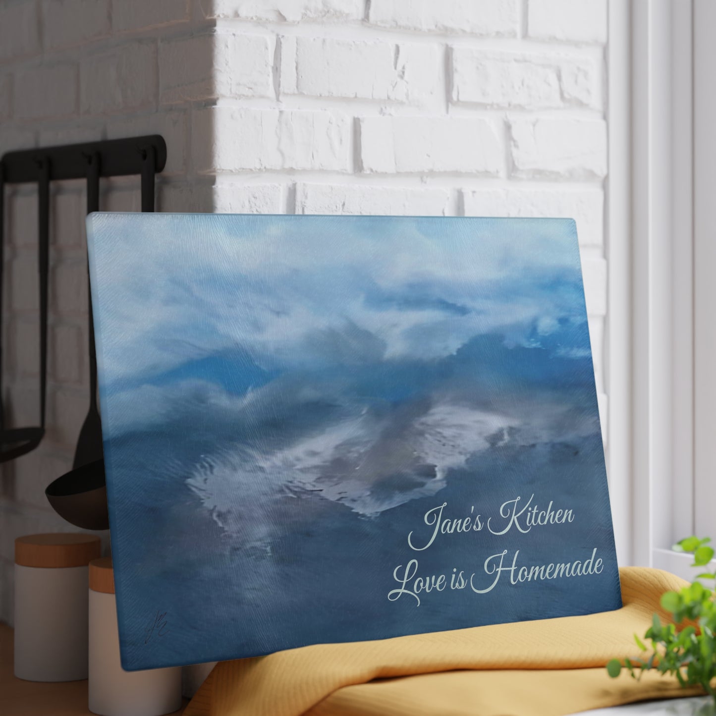 Decorative tempered glass cutting board with abstract art of ocean waves and text in a home setting. Style by Jess
