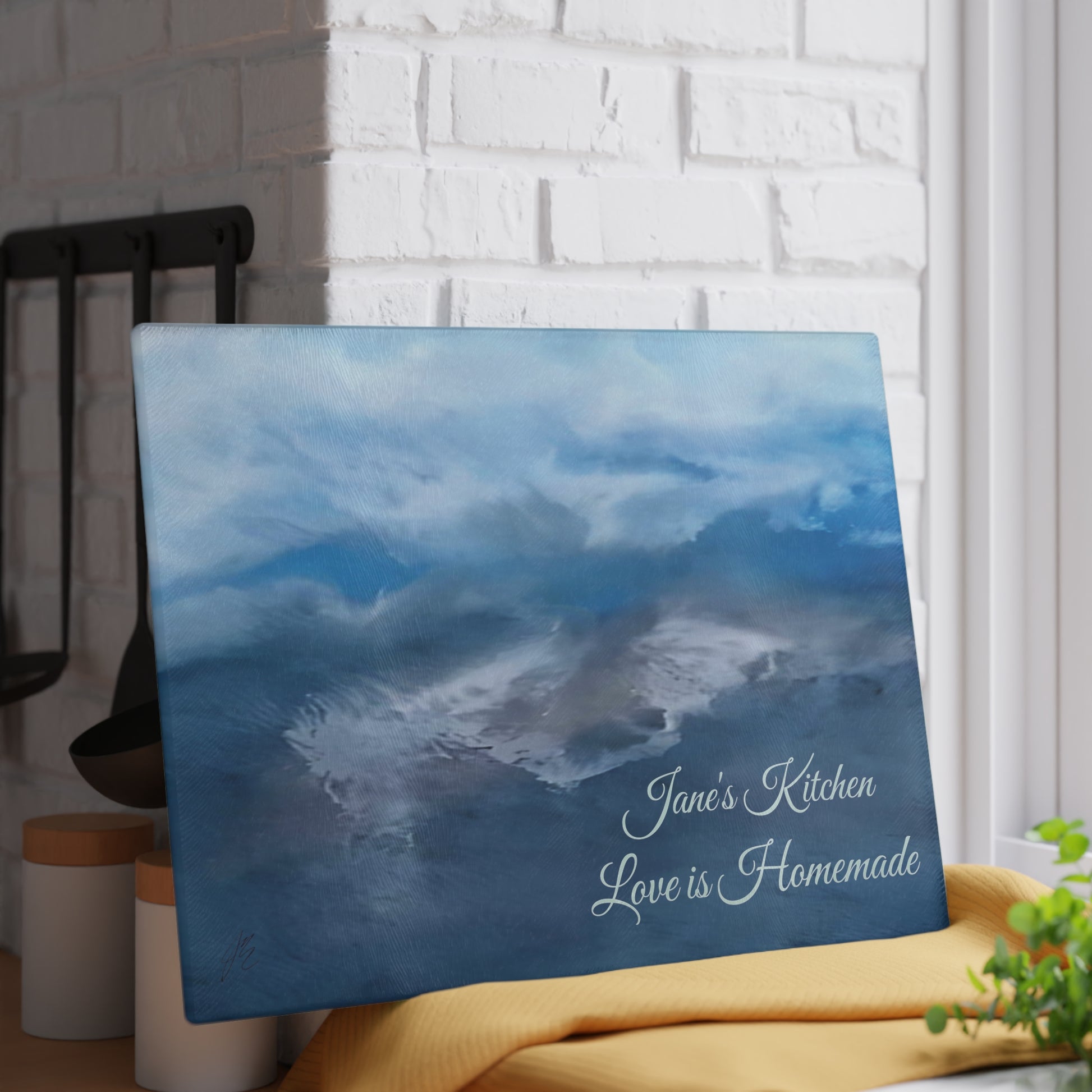 Decorative tempered glass cutting board with abstract art of ocean waves and text in a home setting. Style by Jess