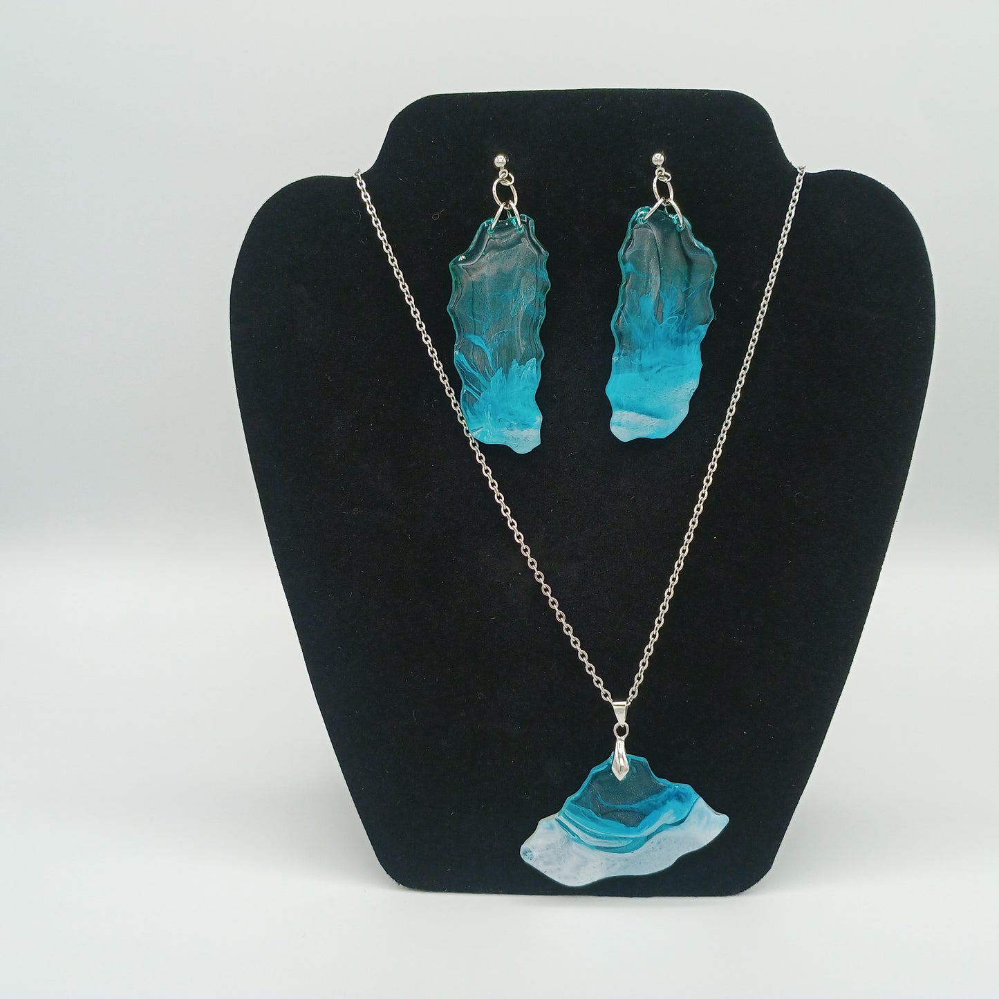 Turquoise and clear necklace and earrings on a black jewelry display stand gift set.