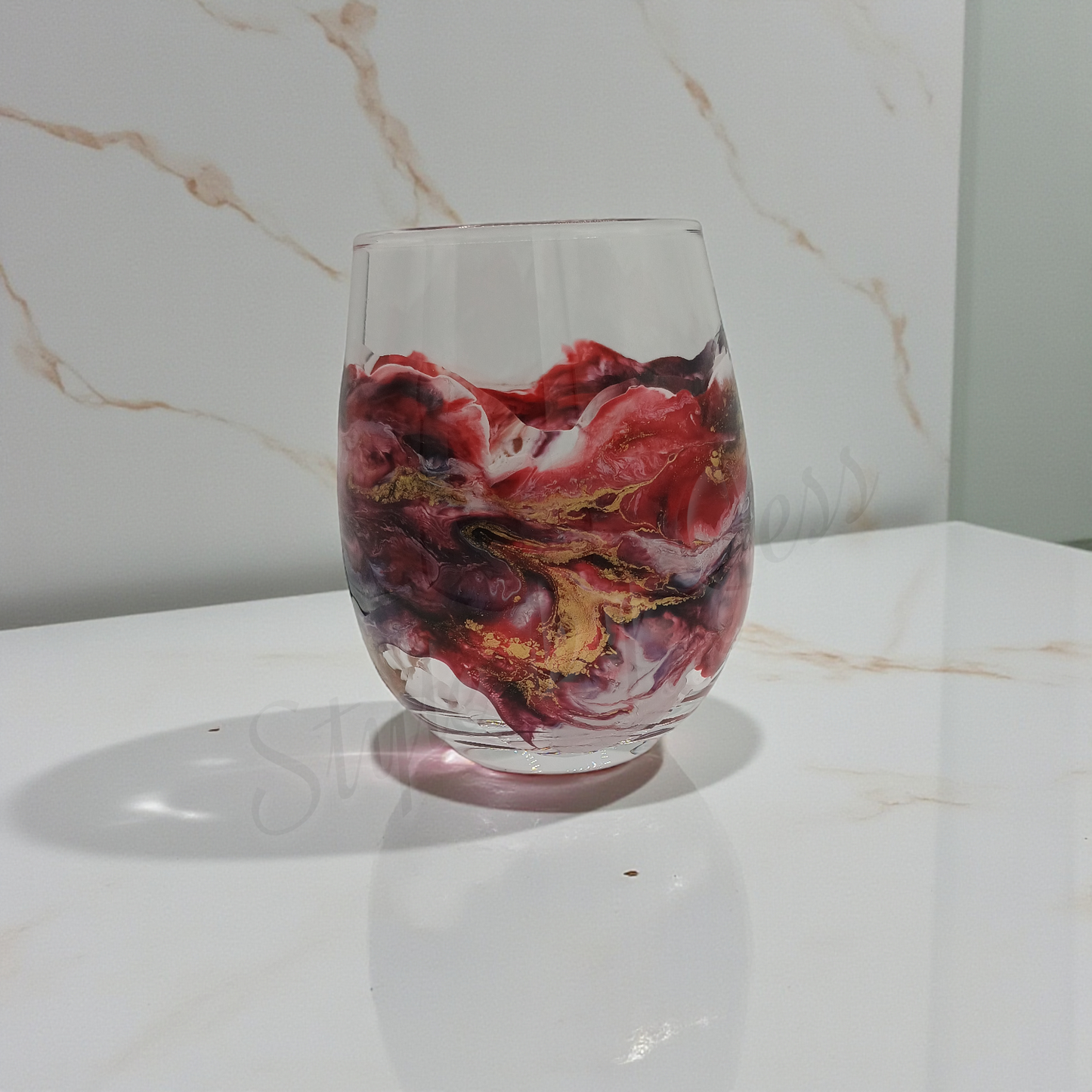 Clear glass with marbled red and gold design on a marble surface