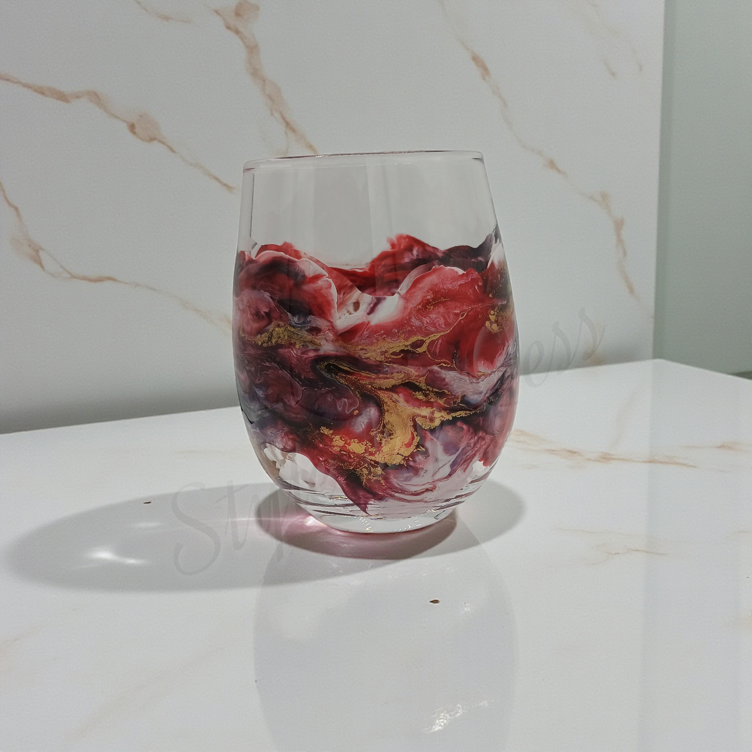 Clear glass with marbled red and gold design on a marble surface