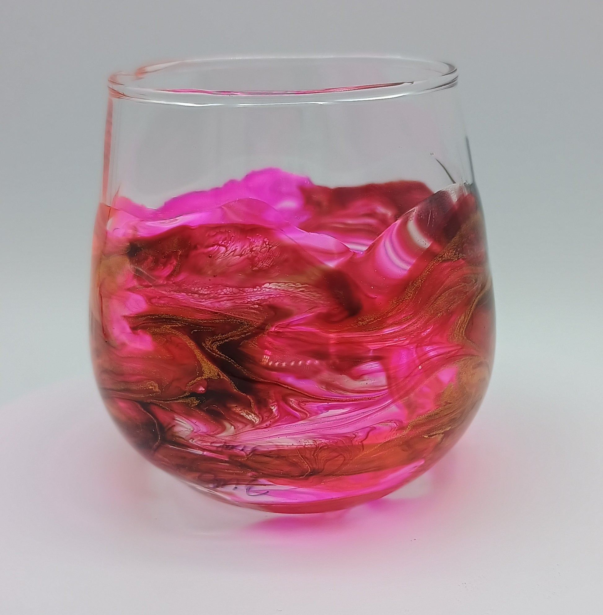 Shot glass with pink and red marbled design on a white background barware