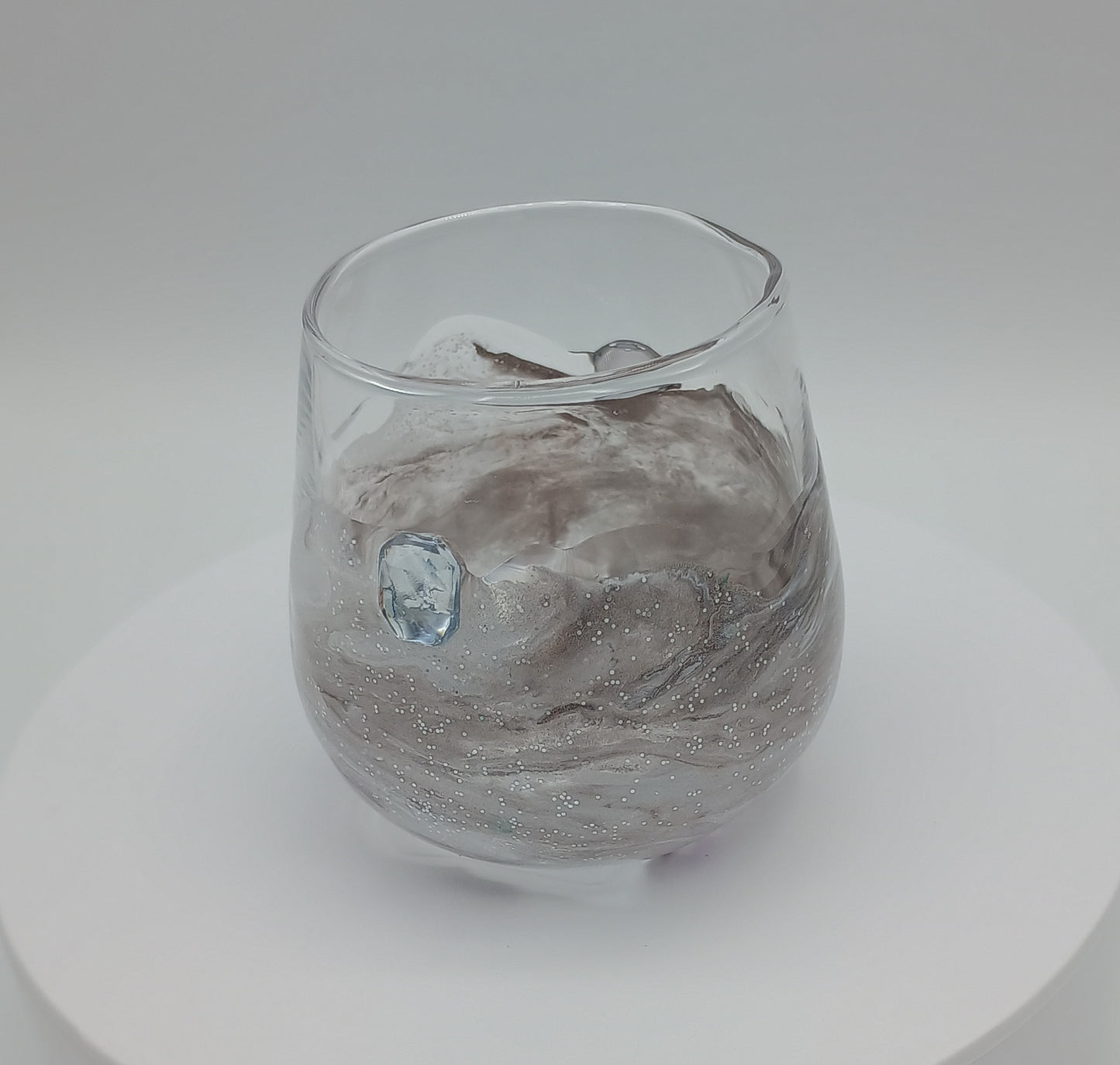 Clear shot glass with white and gray marbled design on a white background