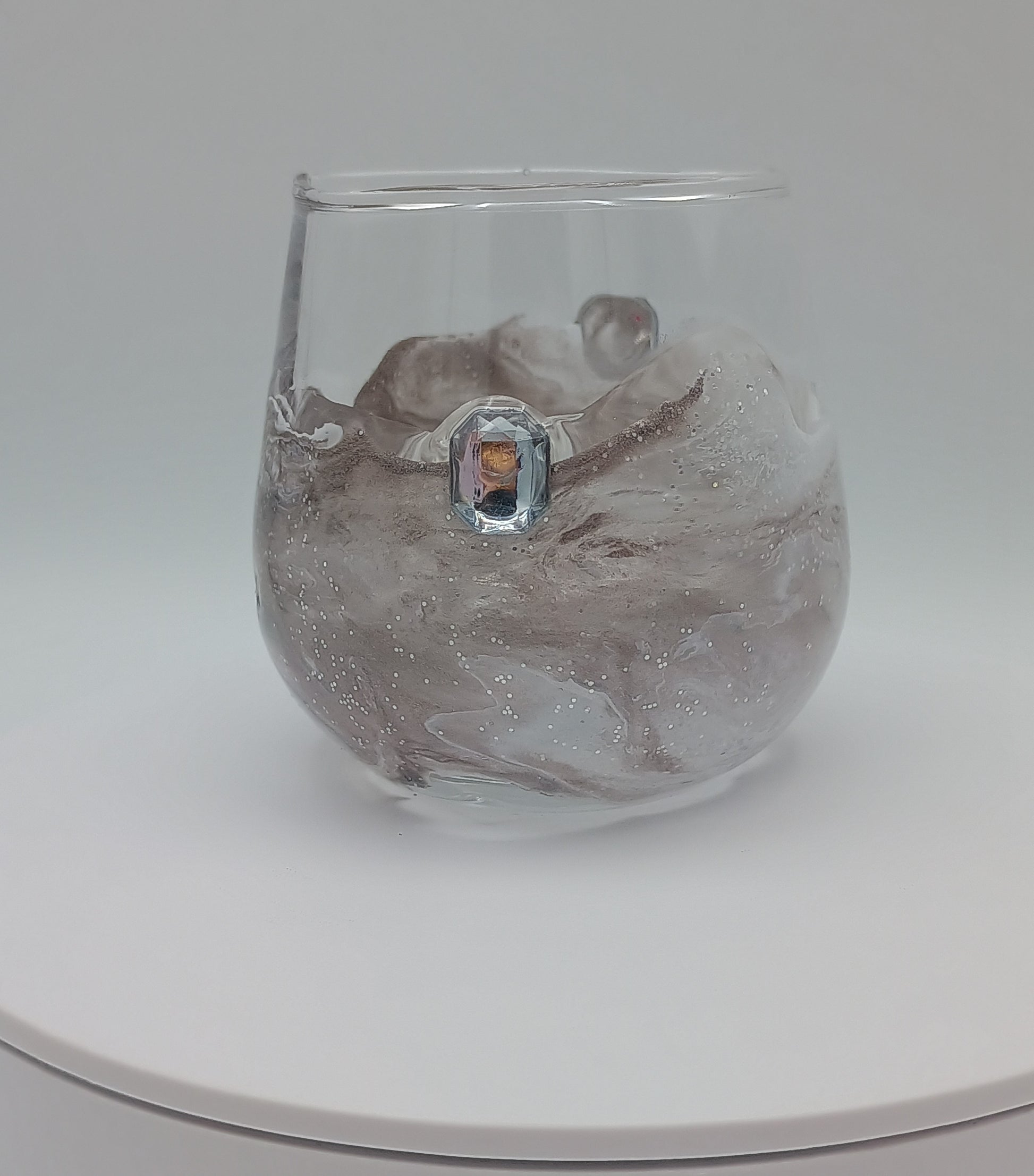 Clear custom shot glass with a decorative abstract art design on a white wedding gift table. 