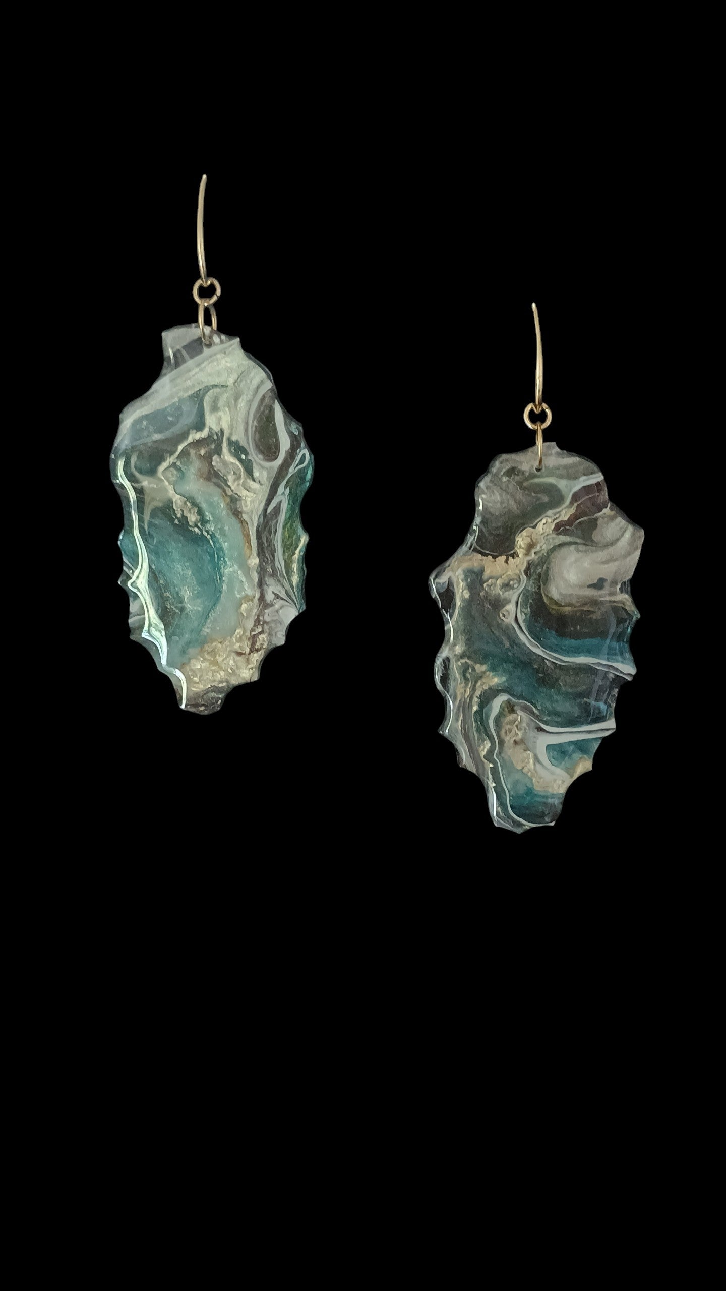 Stylish dangle earrings that are a statement piece with artistic flair.  They have show lots of movement in shades of teal gold and white with 18K gold plated hardware on a black background. A Style By Jess at Gotta Have It Design