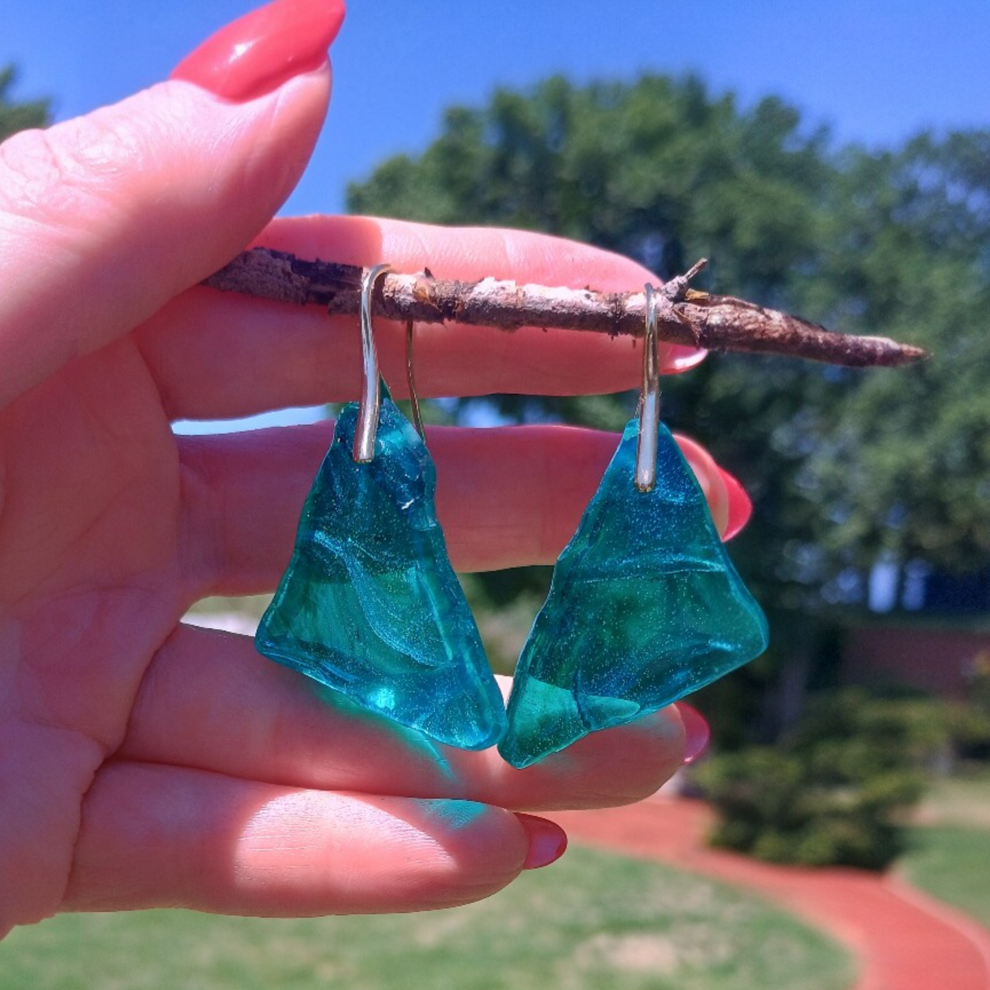 Resin earrings displaying transparency wth 18 K Gold Plated hardware and a green nature background.  A Style by Jess at Gotta Have It Design