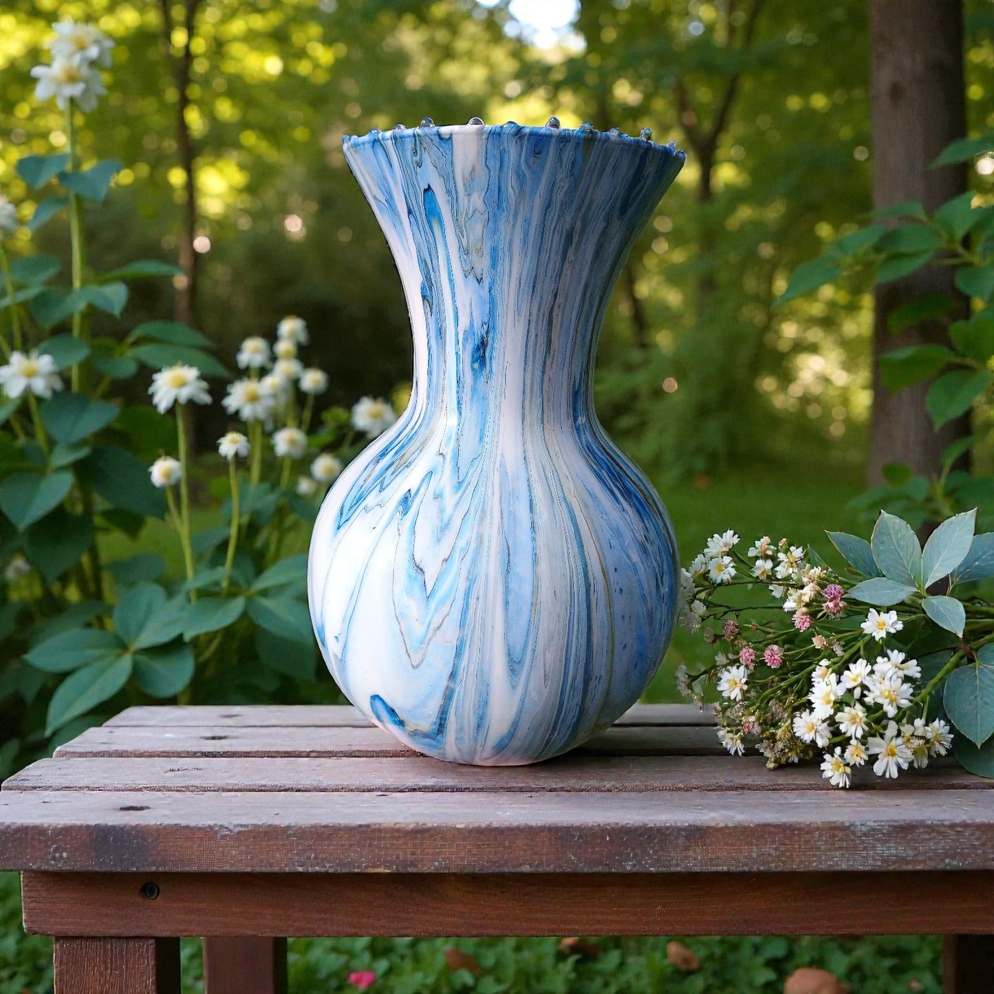 Blue and white marbled vase on a wooden table with flowers in a garden setting