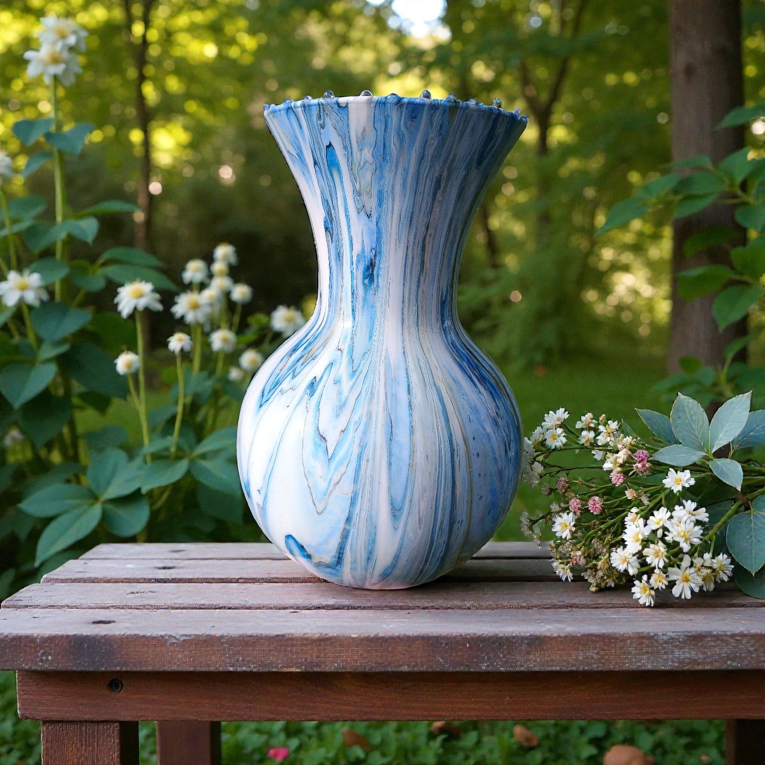 Blue and white marbled vase on a wooden table with flowers in a garden setting