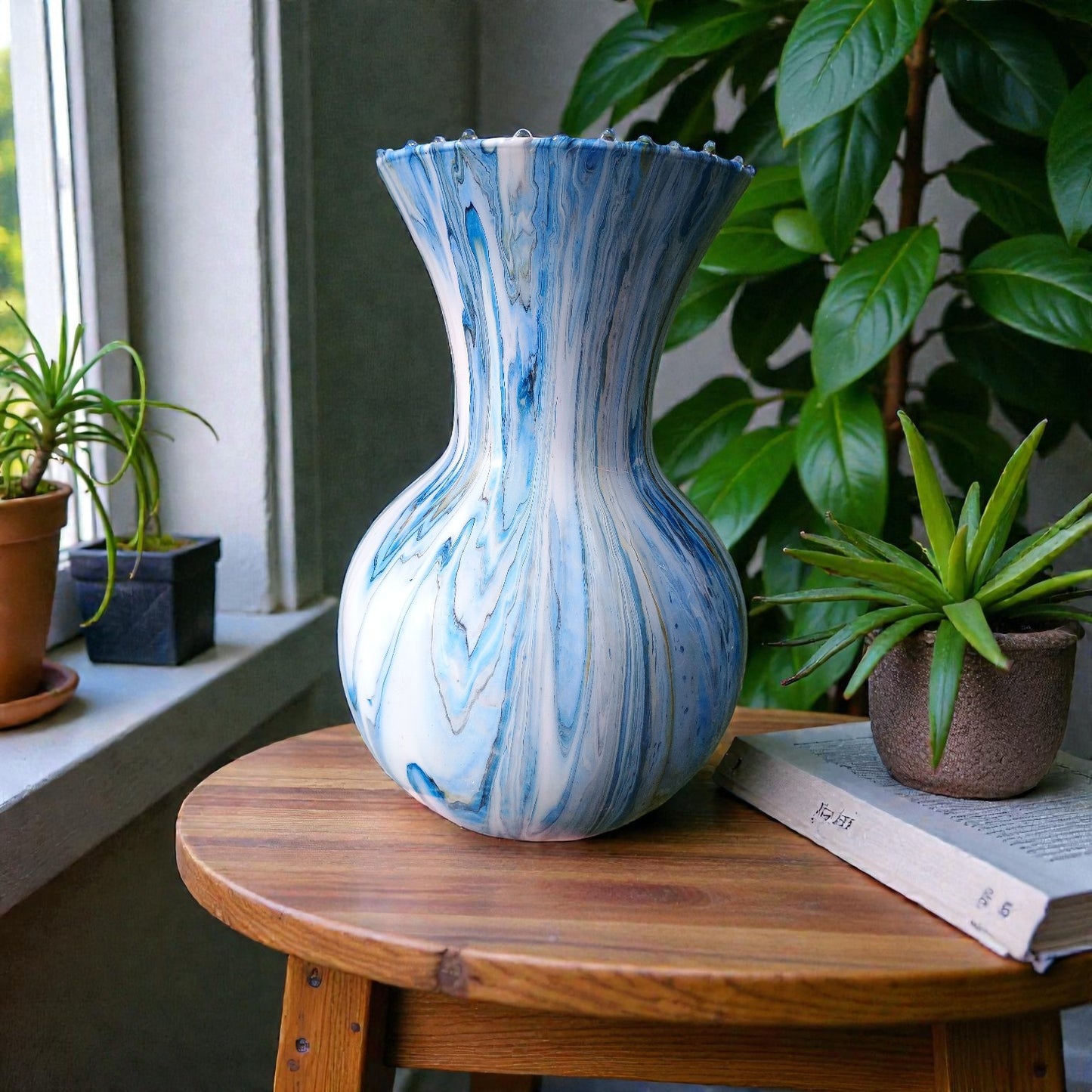Blue and white marbled vase on a wooden table with plants in the background