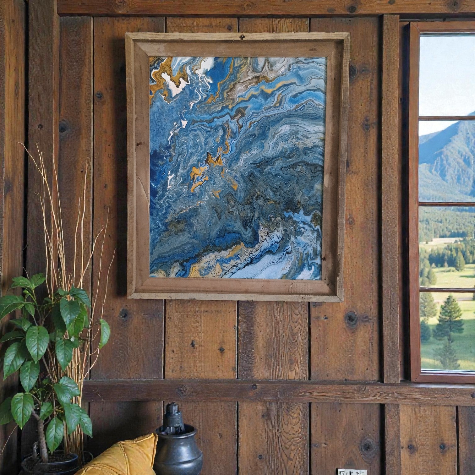 Framed abstract painting on a wooden wall with a window showing a mountain view.