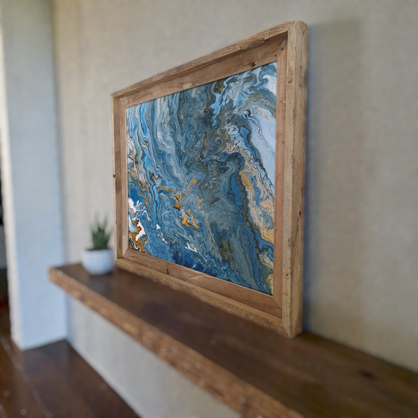 Abstract wall art in a rustic wooden frame on a wall in a boho style living room. 