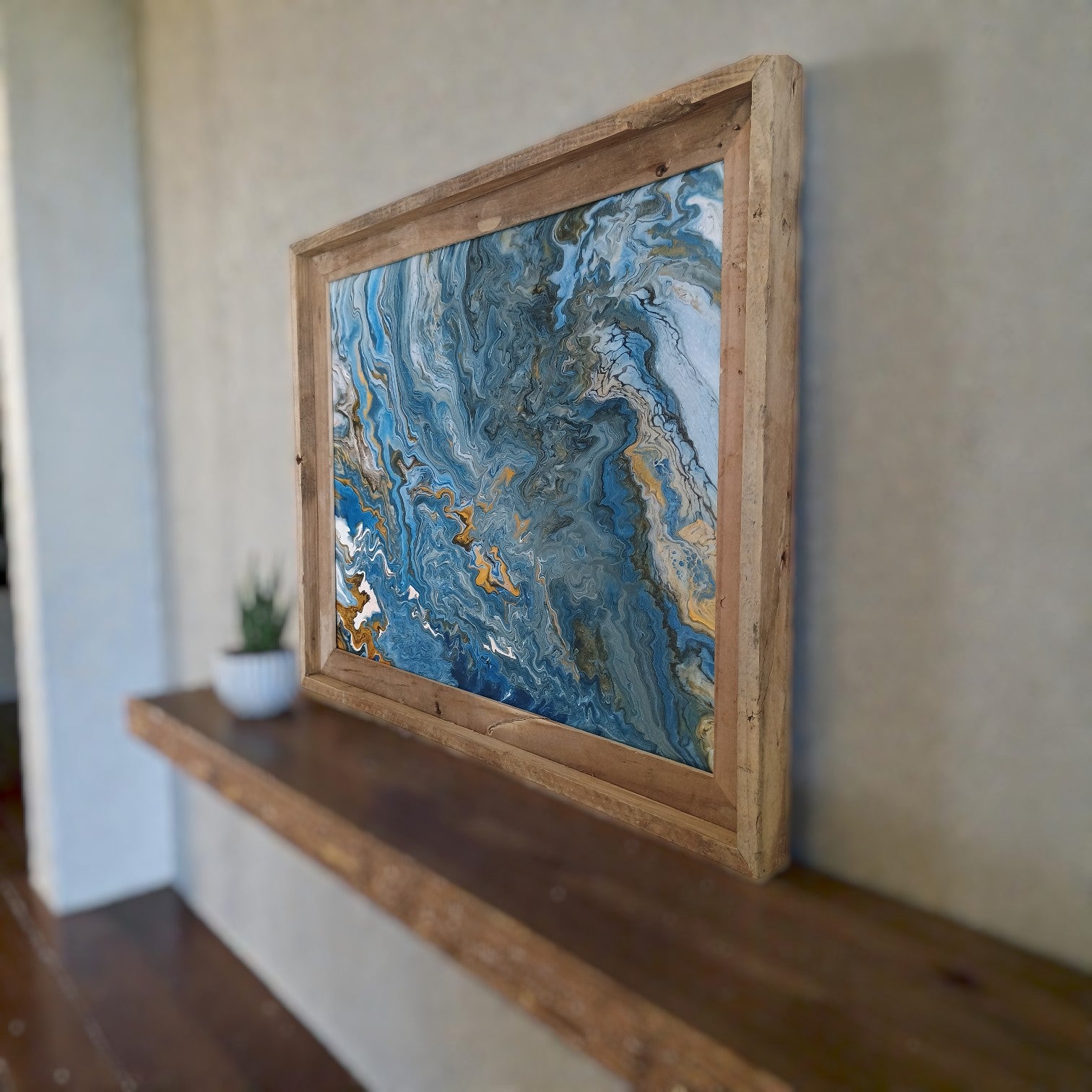 Abstract wall art in a rustic wooden frame on a wall in a boho style living room. 