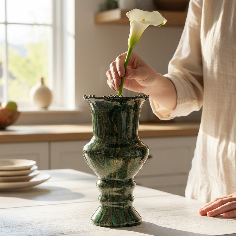 Person arranging a flower in a custom marbled style flower vase on a kitchen counter.