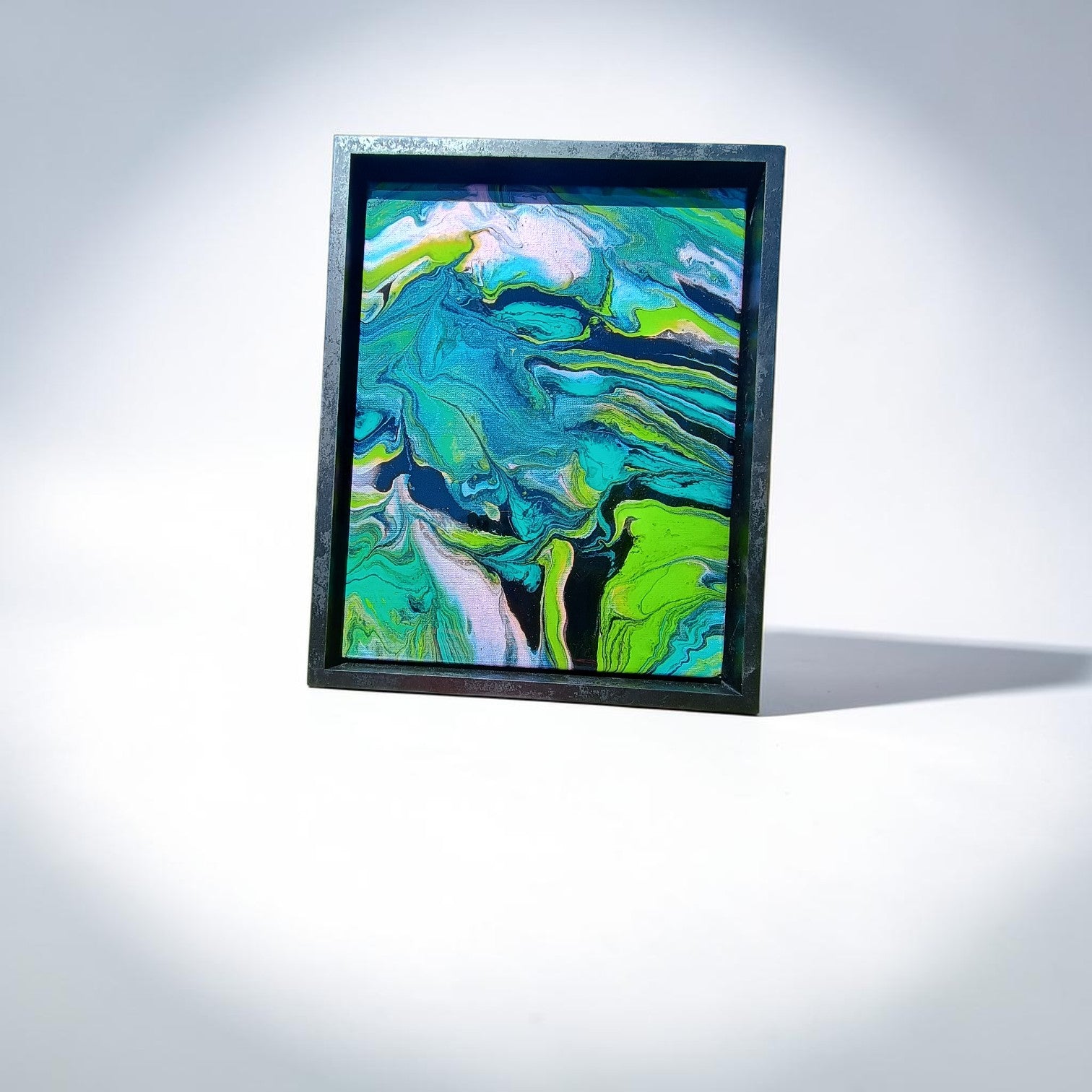 Framed abstract artwork with swirling green, blue, and white colors on a light gray background