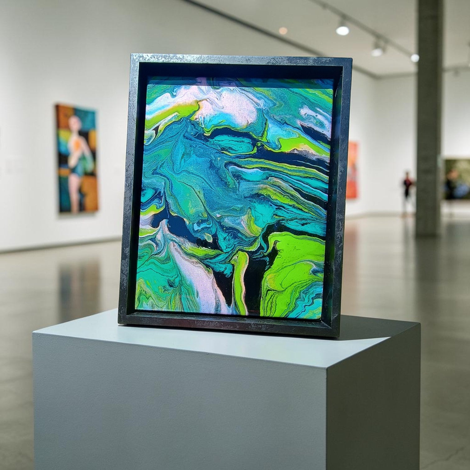 Framed abstract artwork on a pedestal in an art gallery setting