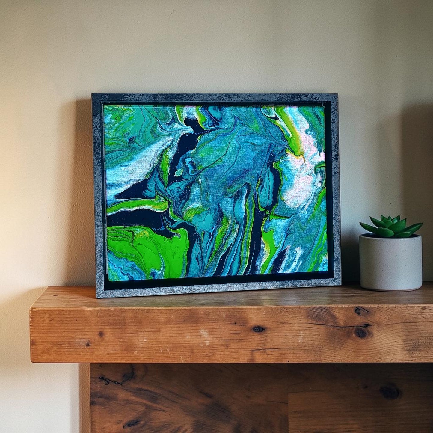 Abstract painting with swirling green and blue colors on a wooden surface displayed as home decor in a living room. 