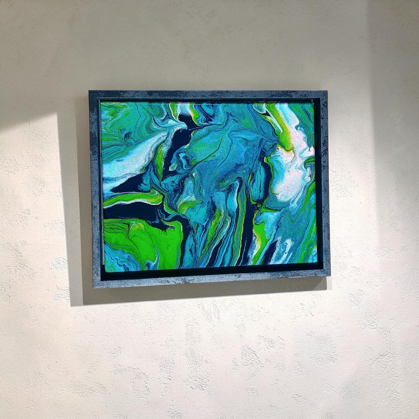Abstract painting with swirling green, blue, and white colors on a light gray wall.