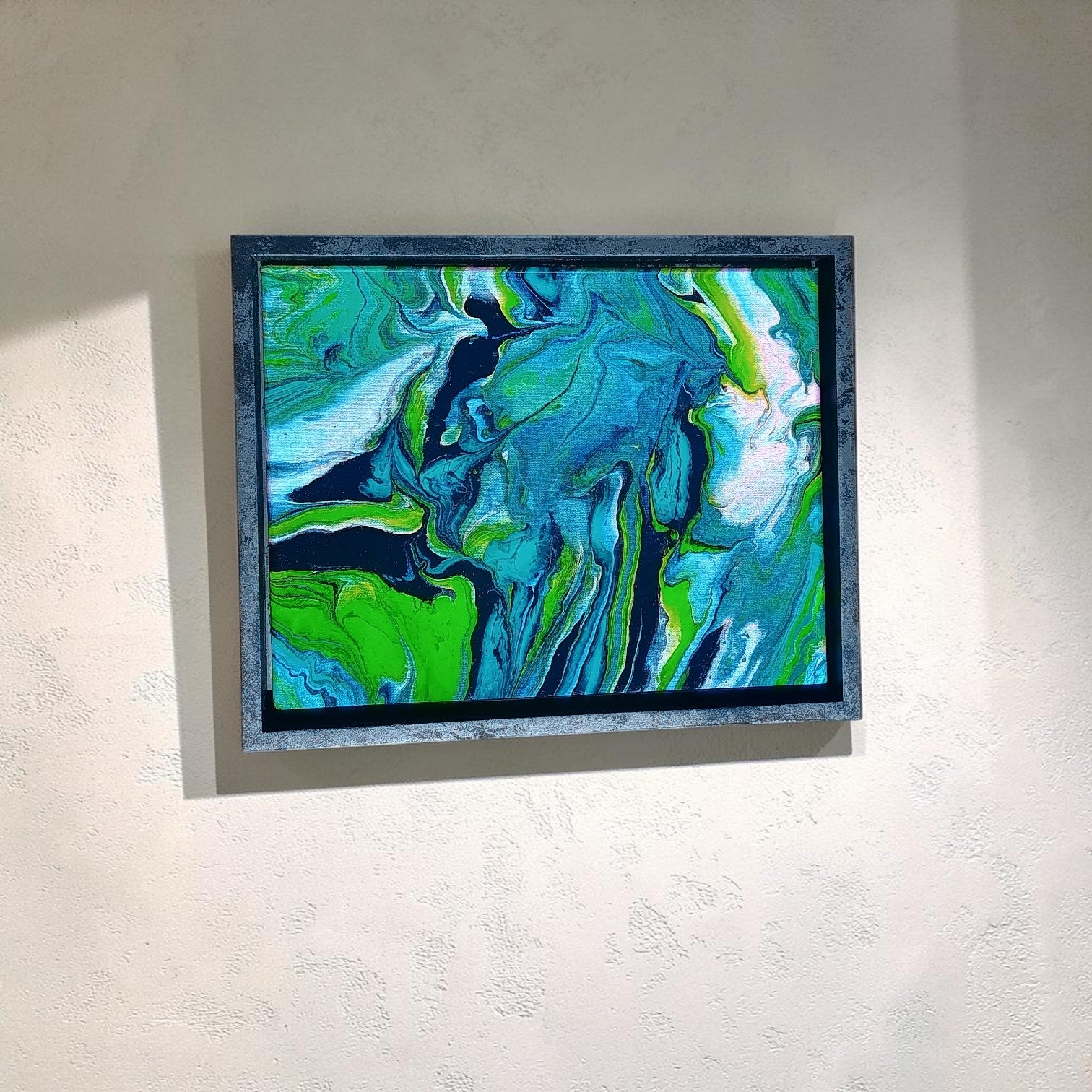 Abstract painting with swirling green, blue, and white colors on a light gray wall.