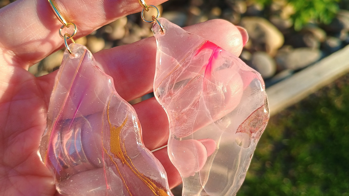 Pink and clear resin earrings held in a hand with a blurred natural background a Style By Jess at Gotta Have It Design