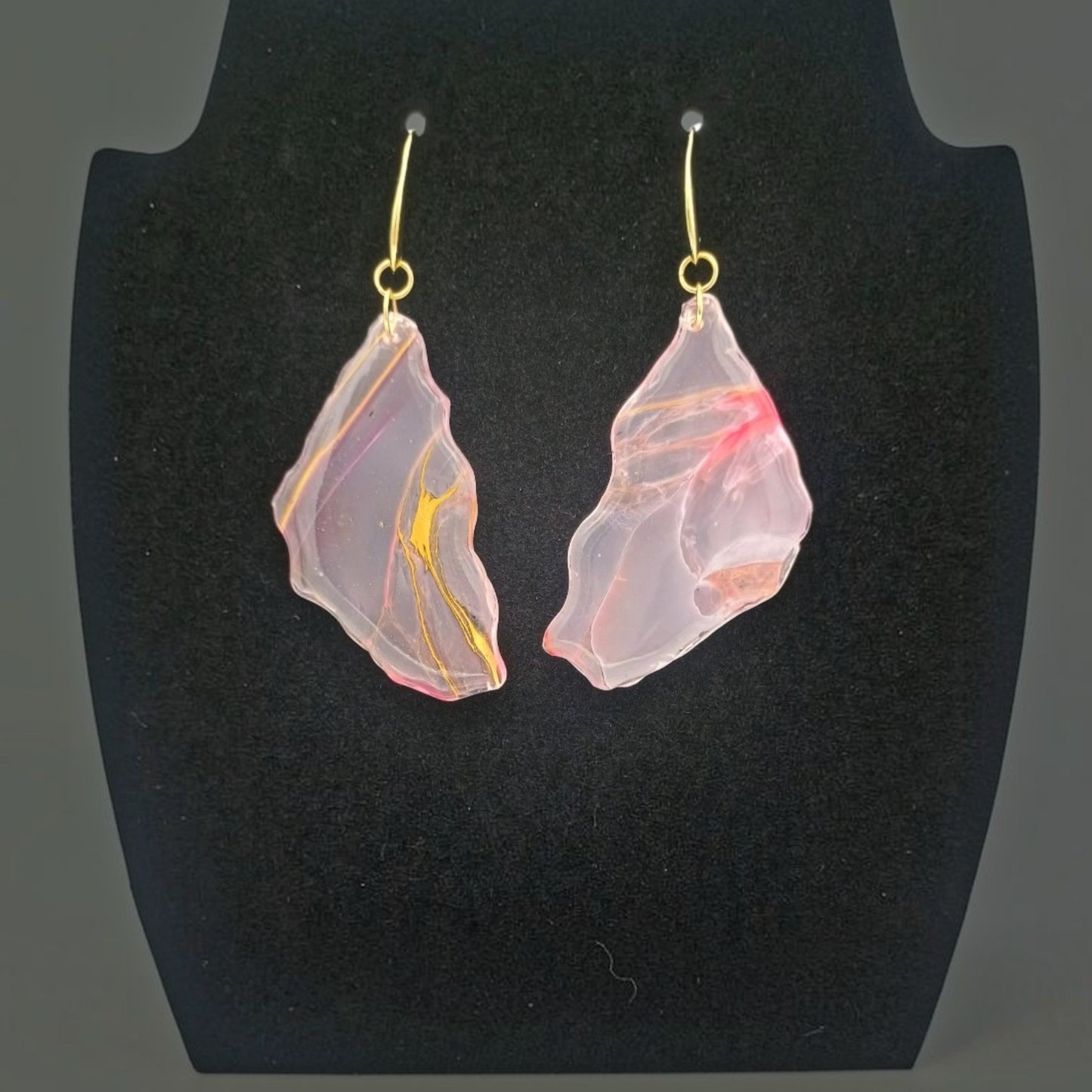 Pink and gold leaf-shaped large earrings on a black stand