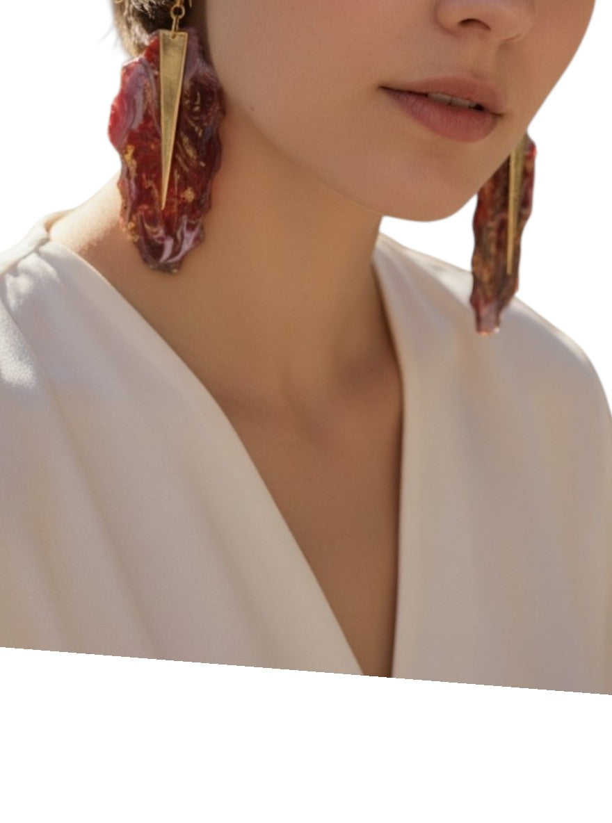 Close-up of a person wearing large, ornate earrings with a plain background