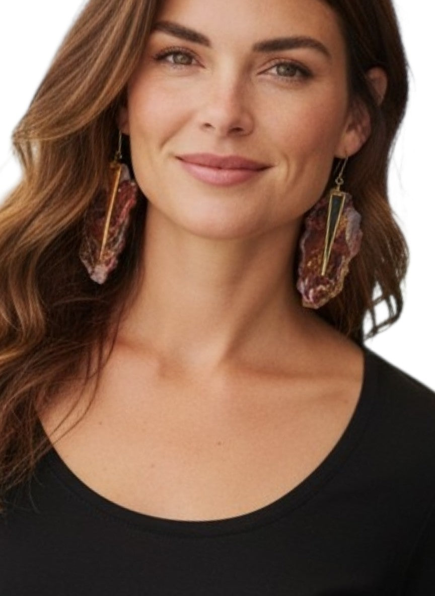 Woman wearing large, designer dangle earrings on a white background making a fashion statement. 