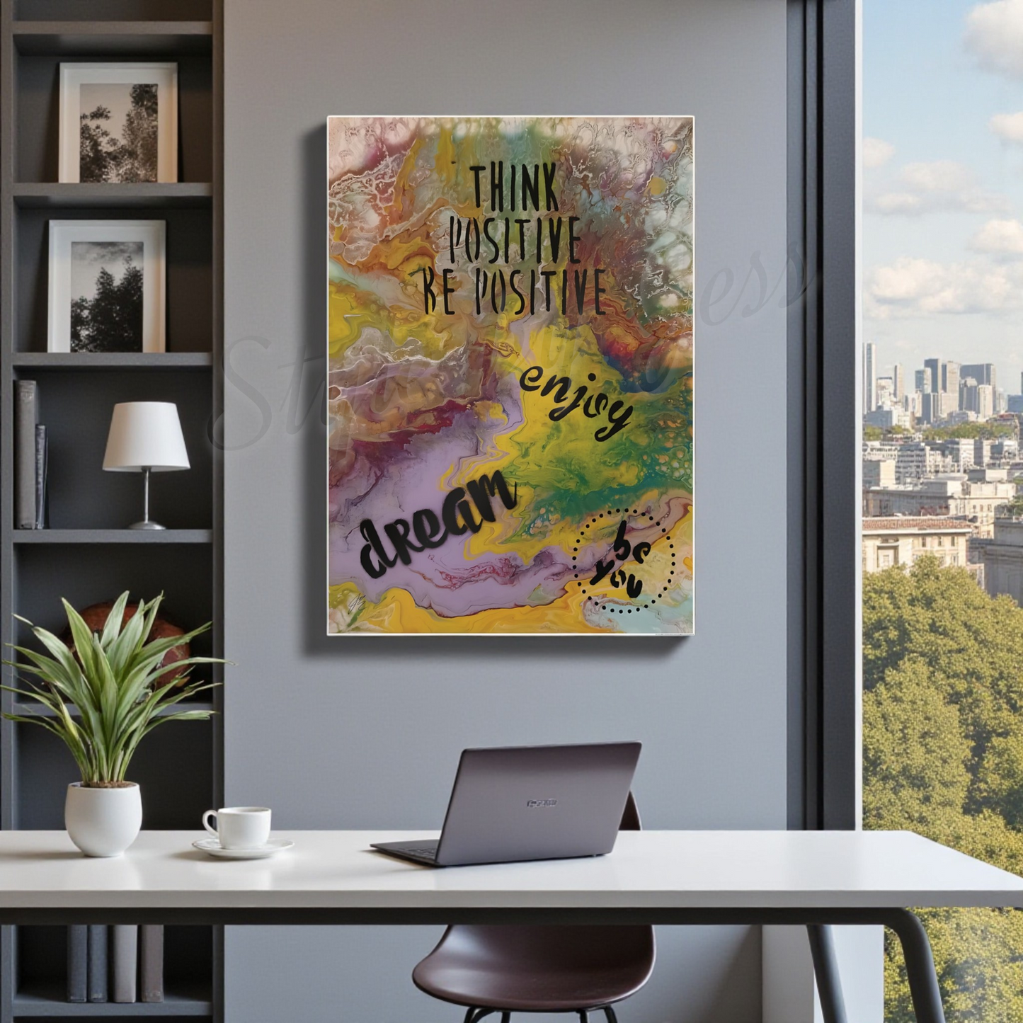 Colorful motivational poster on a wall above a desk with a laptop and plant.