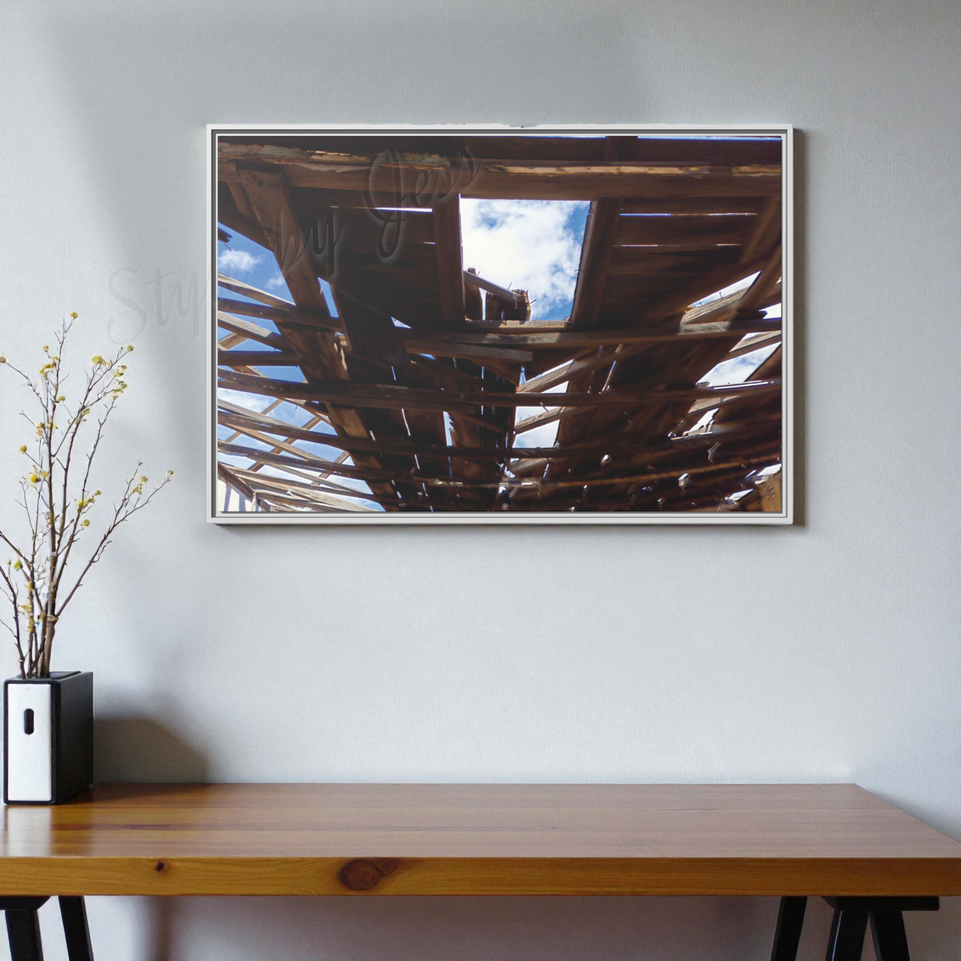 Framed artwork of a ceiling with natural light on a wall above a wooden table.
