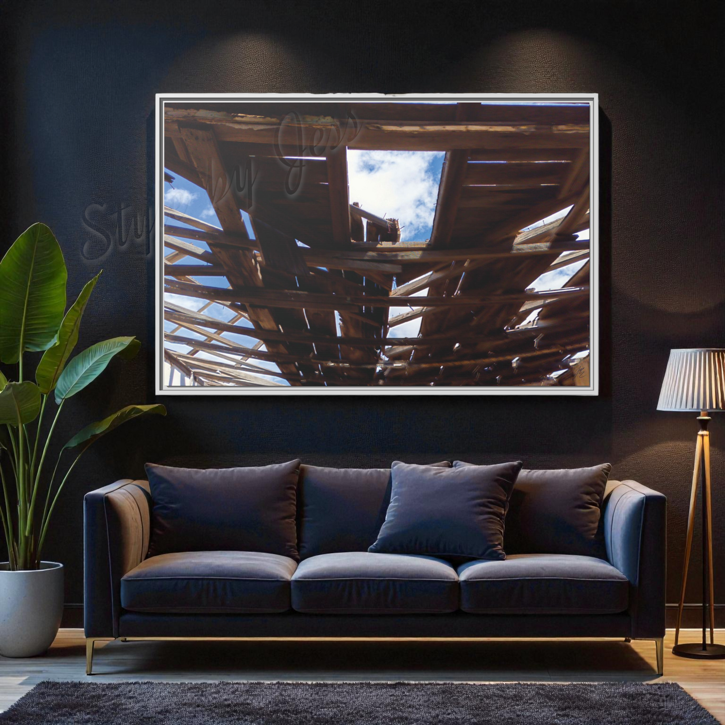Modern living room with a dark blue sofa, rustic framed artwork on the wall, and a plant.