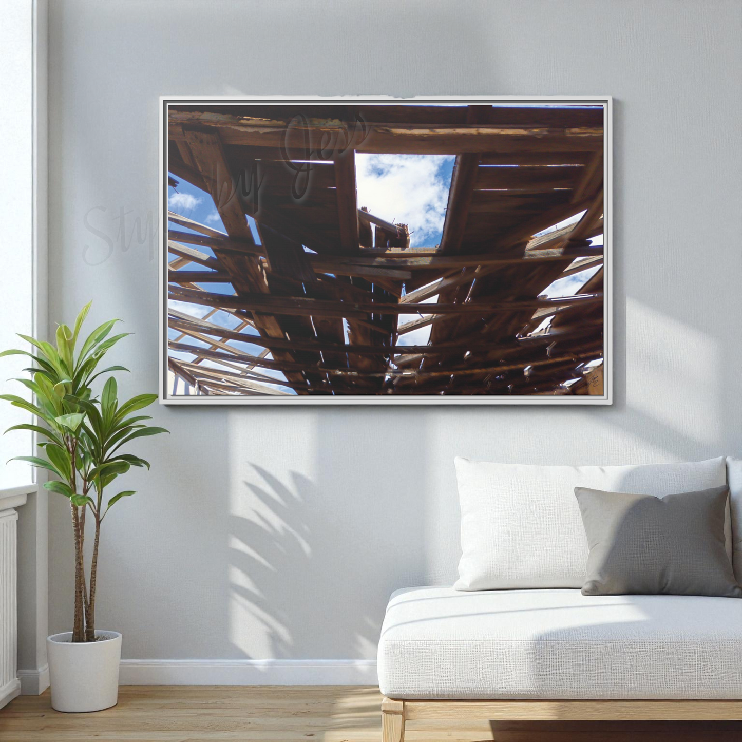 Framed artwork on a wall above a white sofa with a plant to the left.
