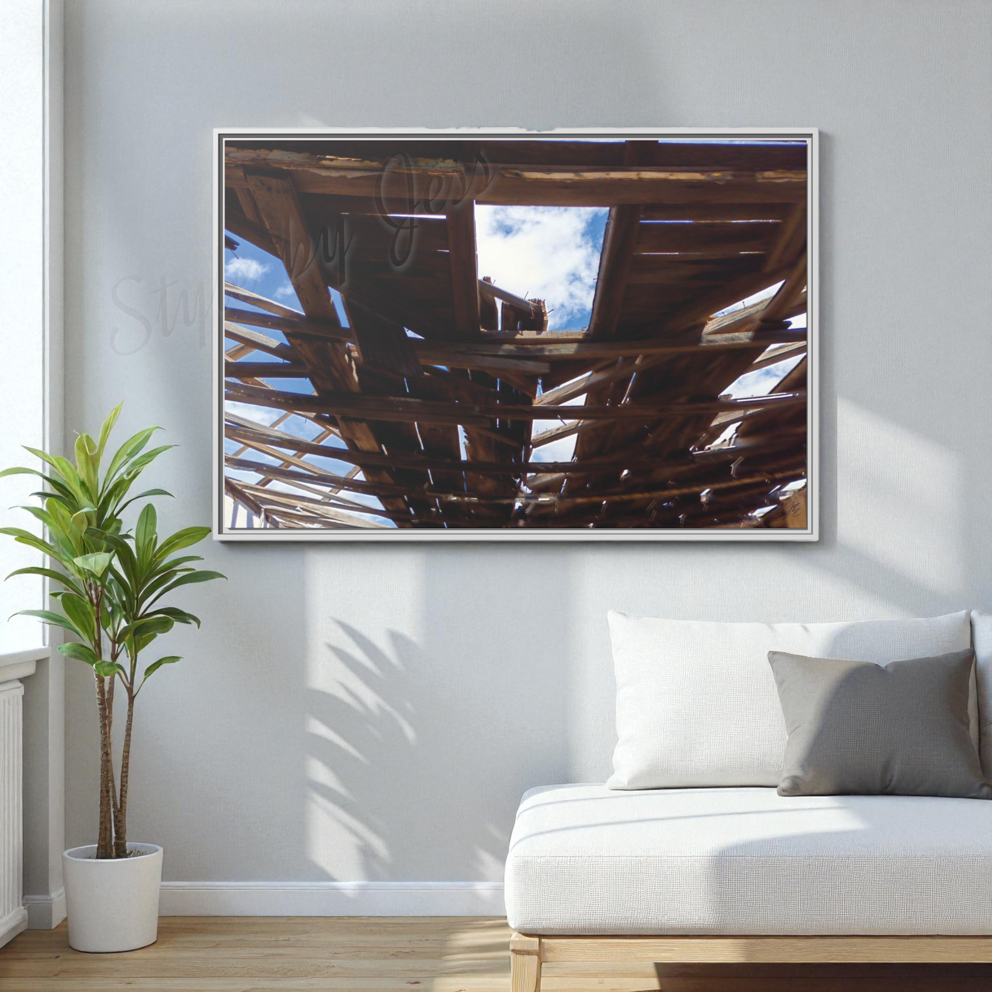 Framed artwork on a wall above a white sofa with a plant to the left.