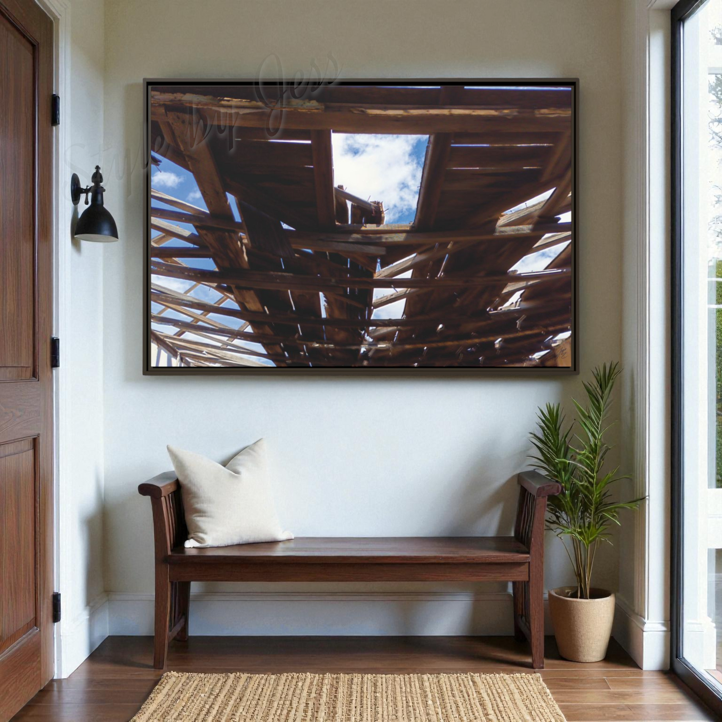 Wooden bench with pillows in a room with a large framed picture of barn wood and a sky on the wall.