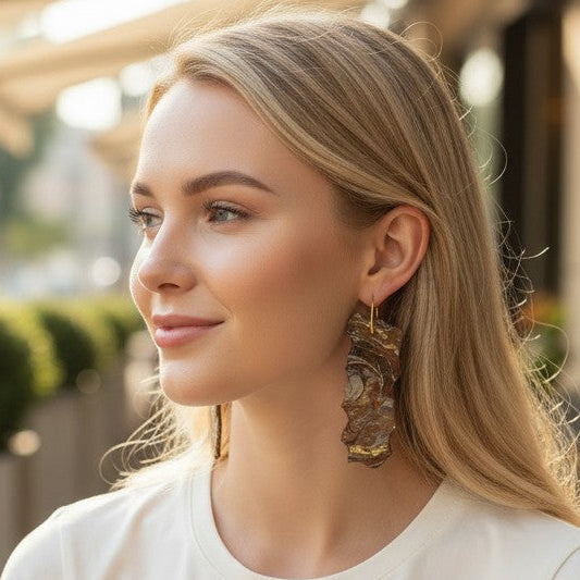 Woman sitting outdoors at a cafe, wearing a white shirt and gold earrings. A Style By Jess at Gotta Have It Design