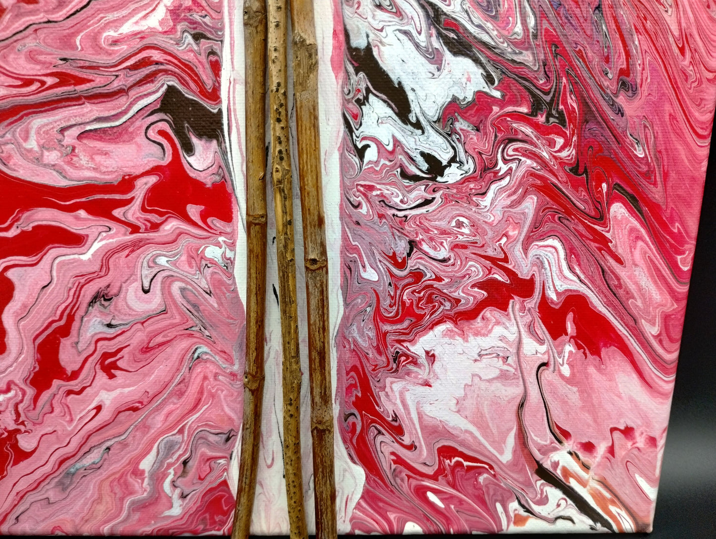 Close up view abstract art piece with pink, white, and red marbled patterns on a dark background.