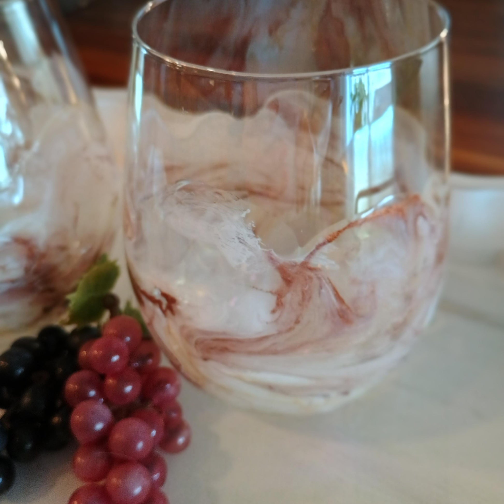Glass with copper and white marbled design on a table with grapes