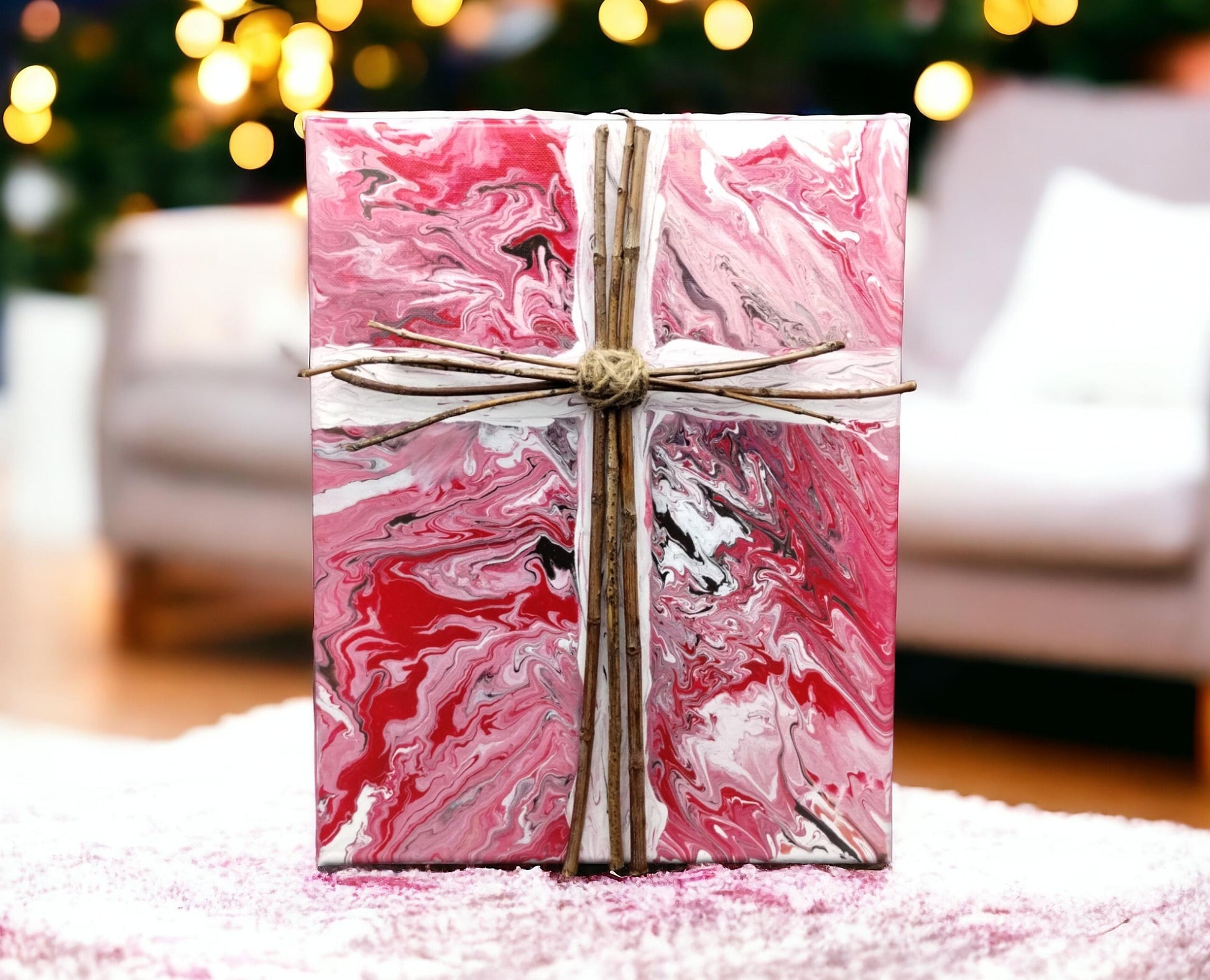 Marbled pink and white canvas painting with a maple wood cross on a soft surface with blurred Christmas lights in the background. Style By Jess