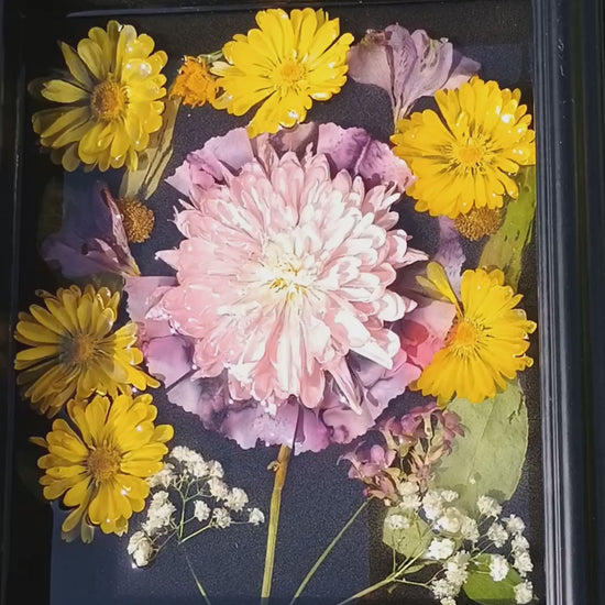 Video of dried flowers emersed in resin framed by a shadow box. 
