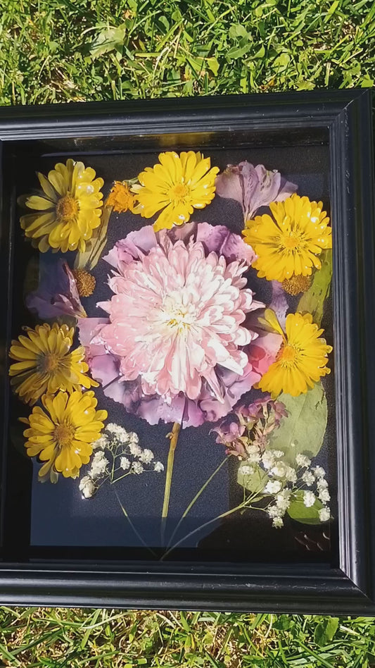 Video of dried flowers emersed in resin framed by a shadow box. 