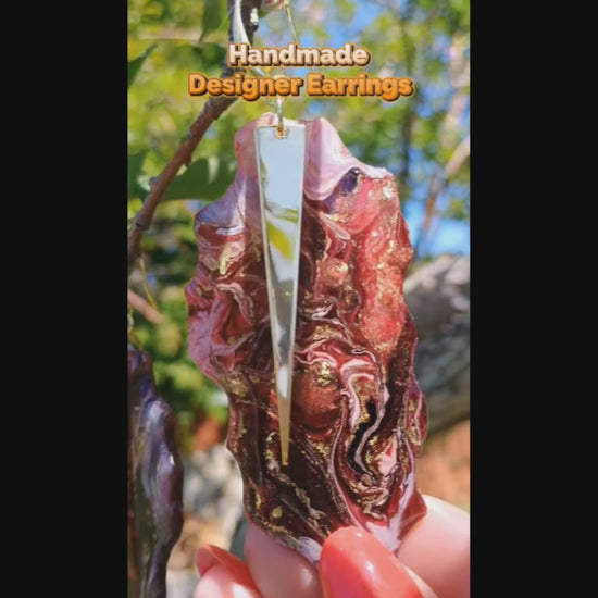 Video of handmade resin earrings displayed in nature showing the gold and red swirls that mimic granite.  Handmade and molded by Jess and is a Style By Jess at Gotta Have It Design. 