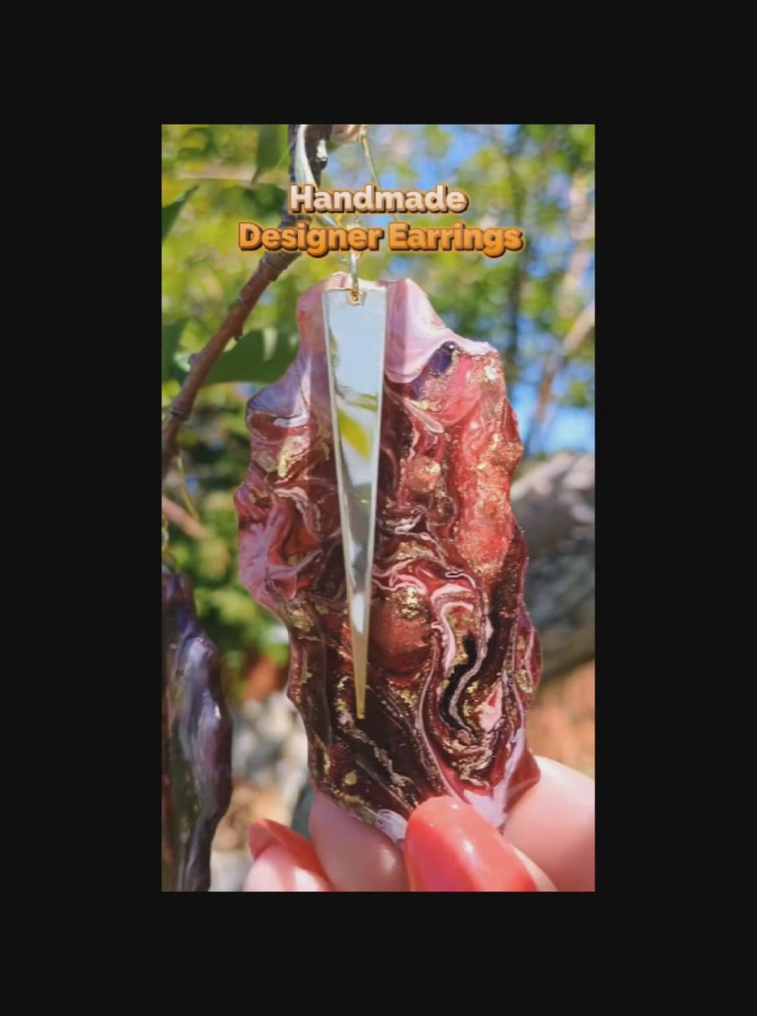 Video of handmade resin earrings displayed in nature showing the gold and red swirls that mimic granite.  Handmade and molded by Jess and is a Style By Jess at Gotta Have It Design. 