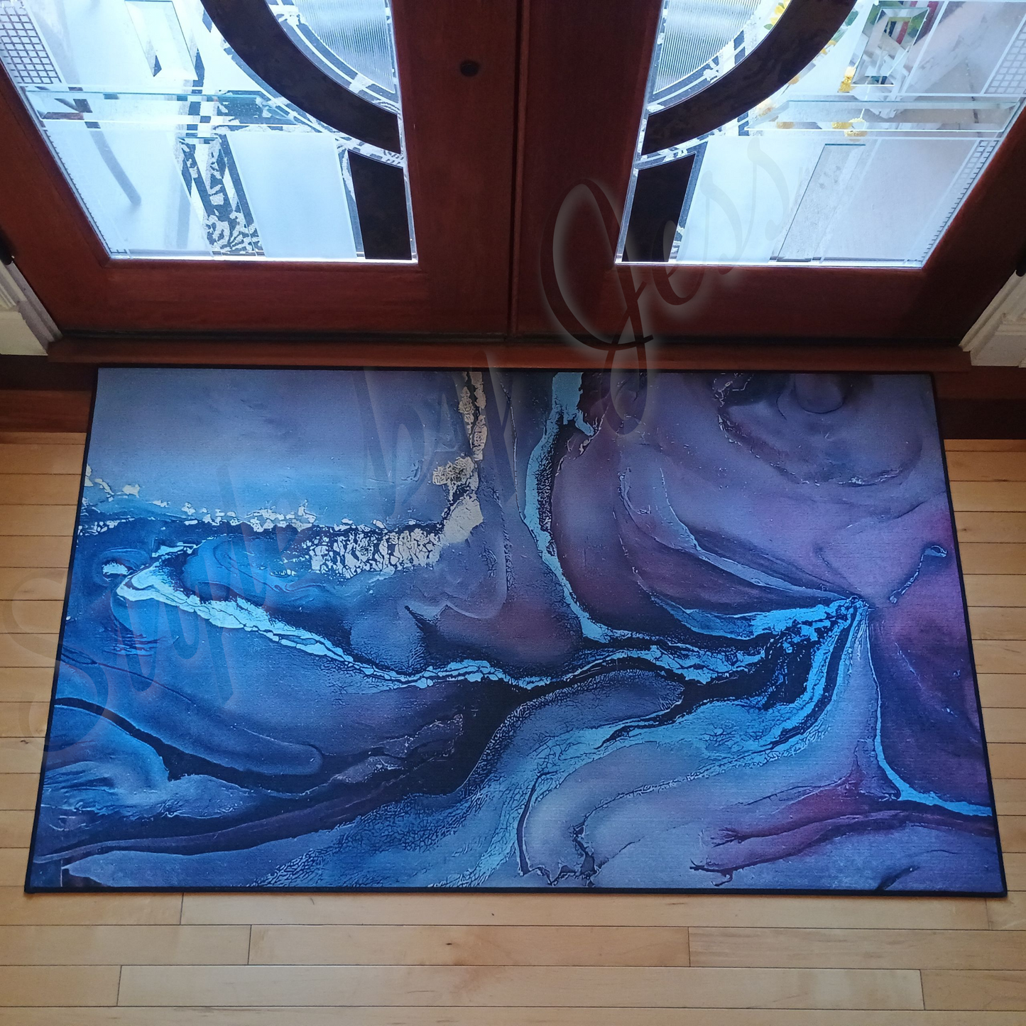 Abstract blue rug on a wooden floor in front of glass doors.