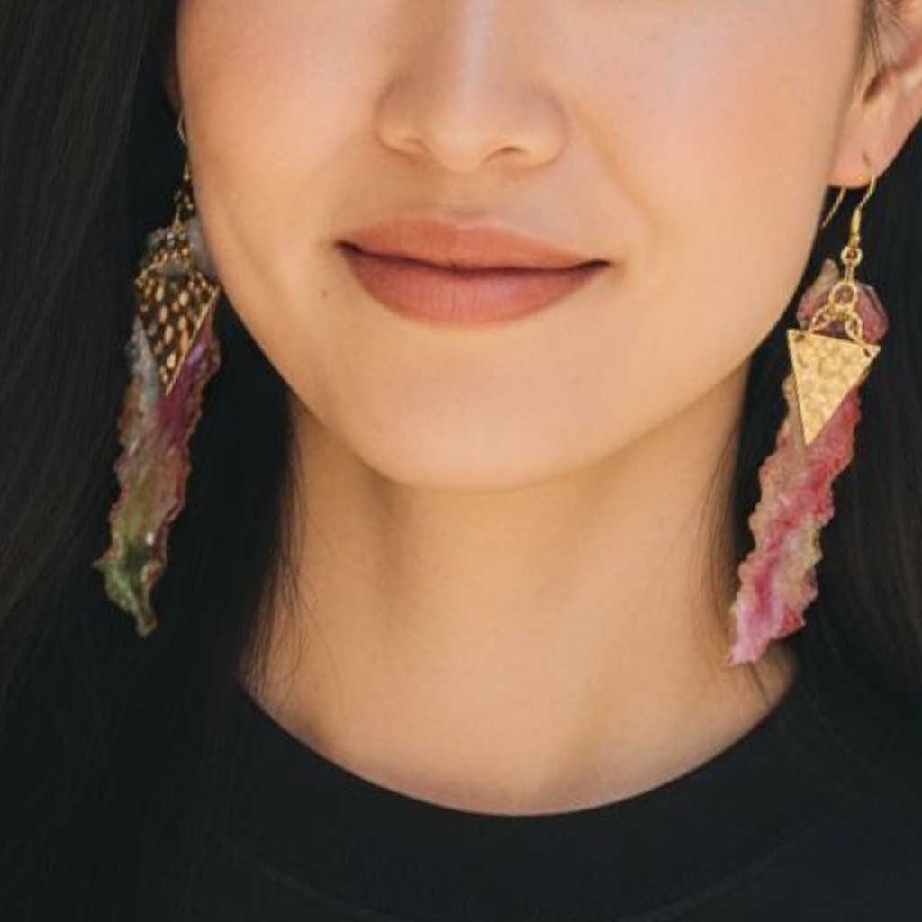 Close-up of a person wearing gold and pink earrings.