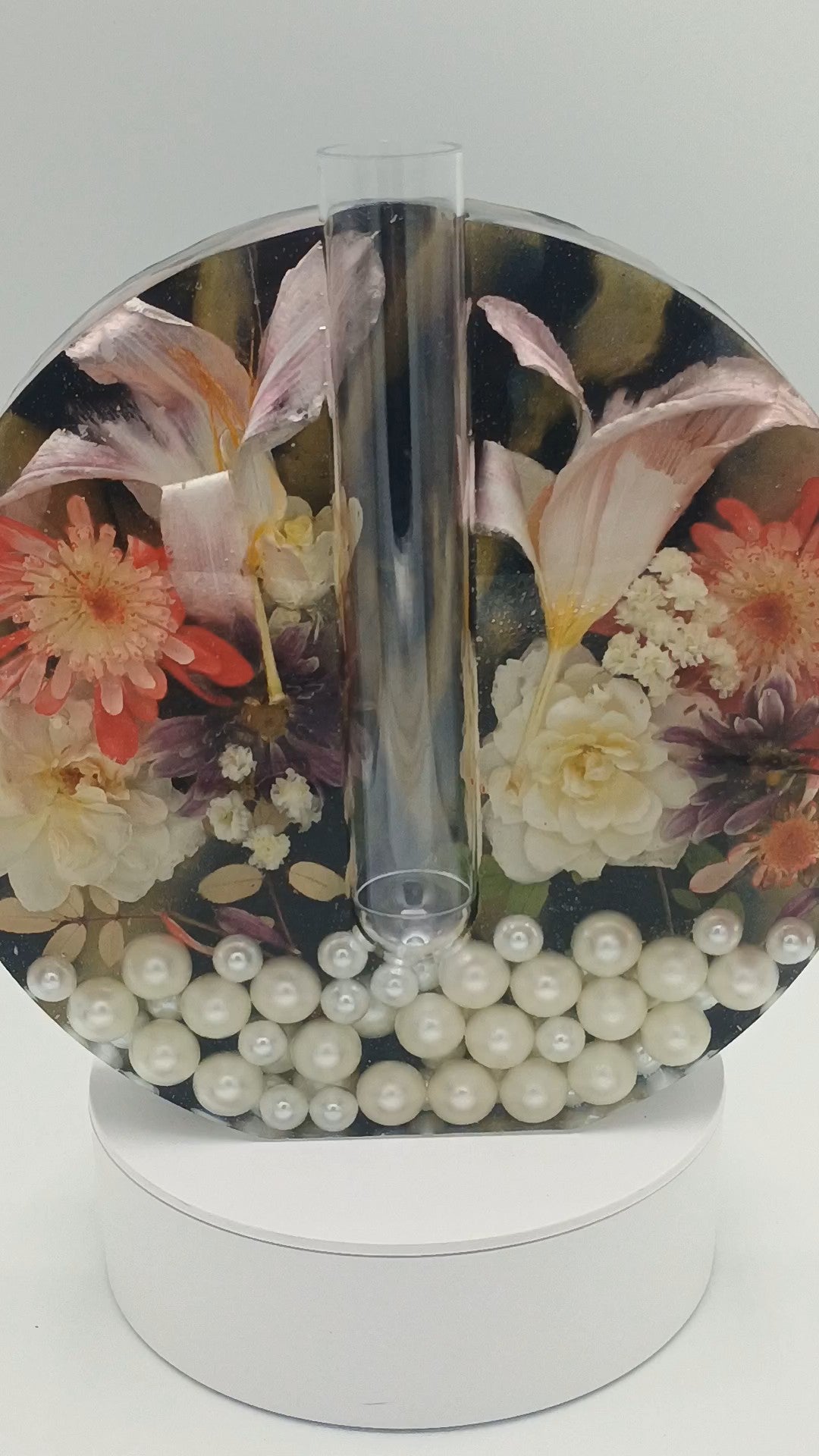 Round decorative item with floral design and pearls on a white background