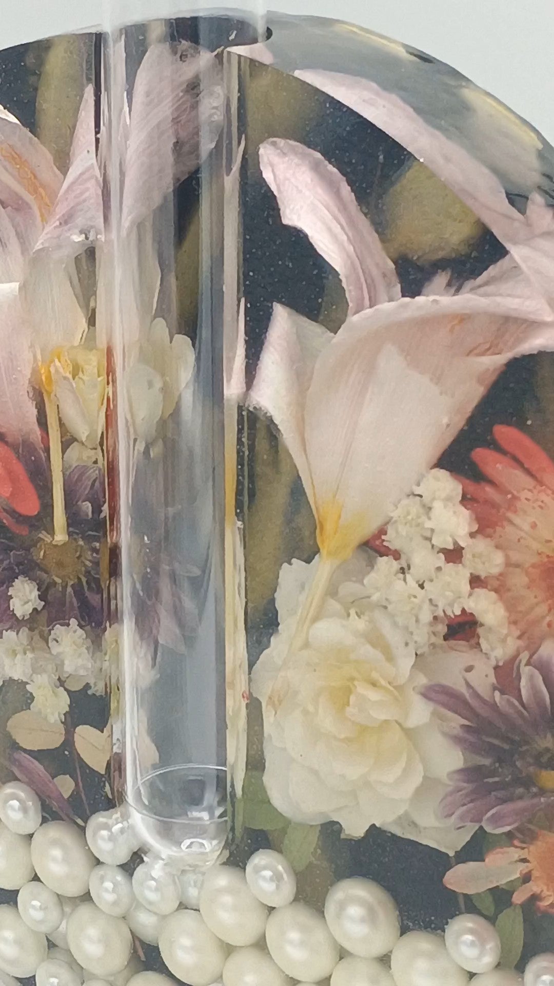 Clear vase with a propaganda tube with real floral design submerged in a deep layer of resin  on a white background a Style By Jess at Gotta Have It Design. 