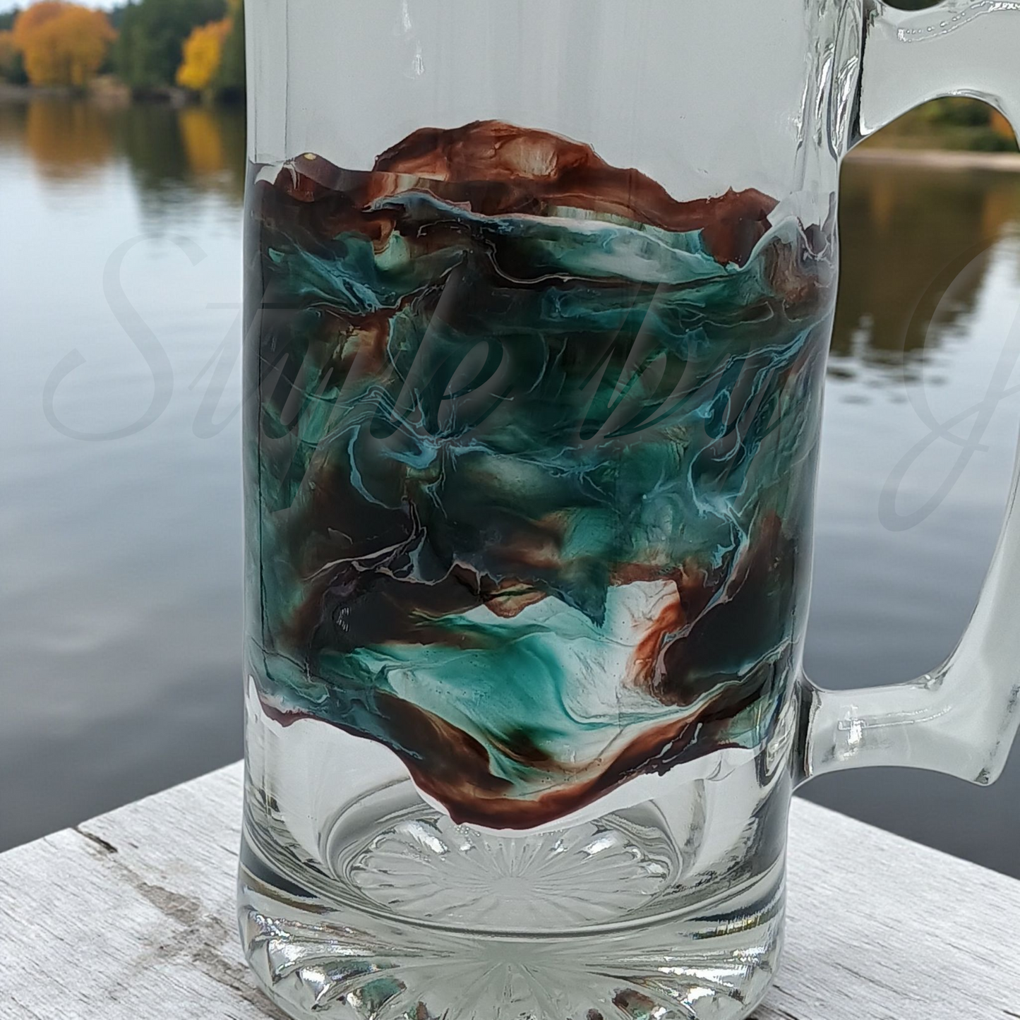 Custom glass mug with marbled design with bluish greens and browns by a body of water giving the feeling of having a drink on the dock of the bay. A dad gift that adds beauty to relaxation. 