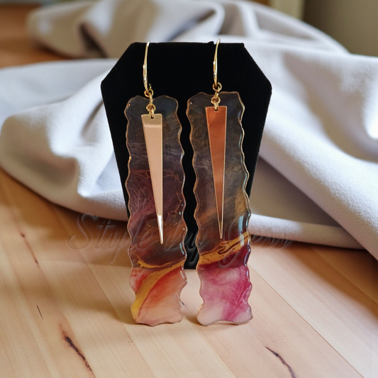 Pair of earrings on a black stand with a white cloth background Style by Jess