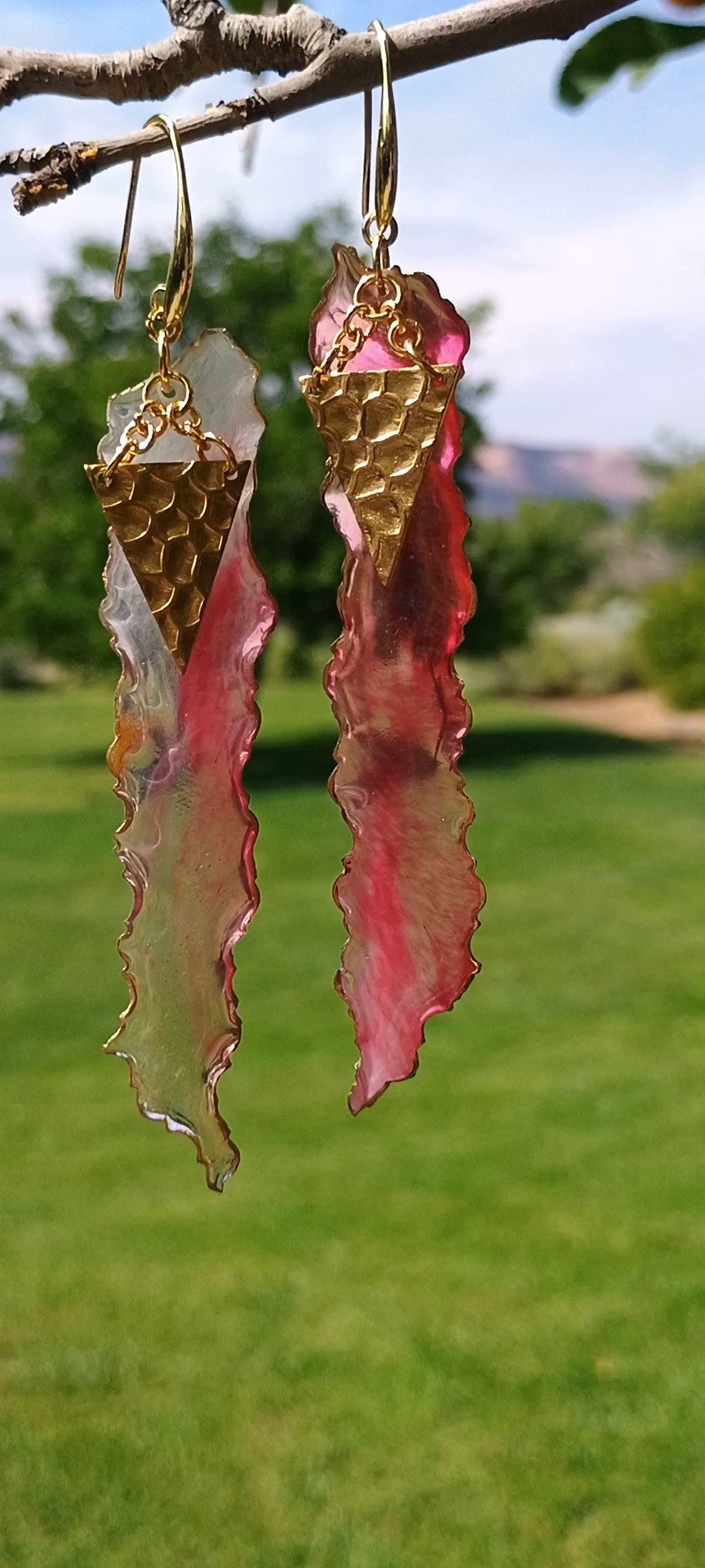 Pair of earrings with gold and pink designs hanging from a branch. Syle by Jess Gotta Have It Design