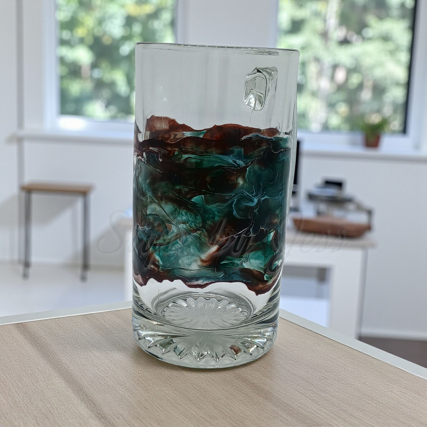 Custom resin art design on a glass mug on a wooden surface