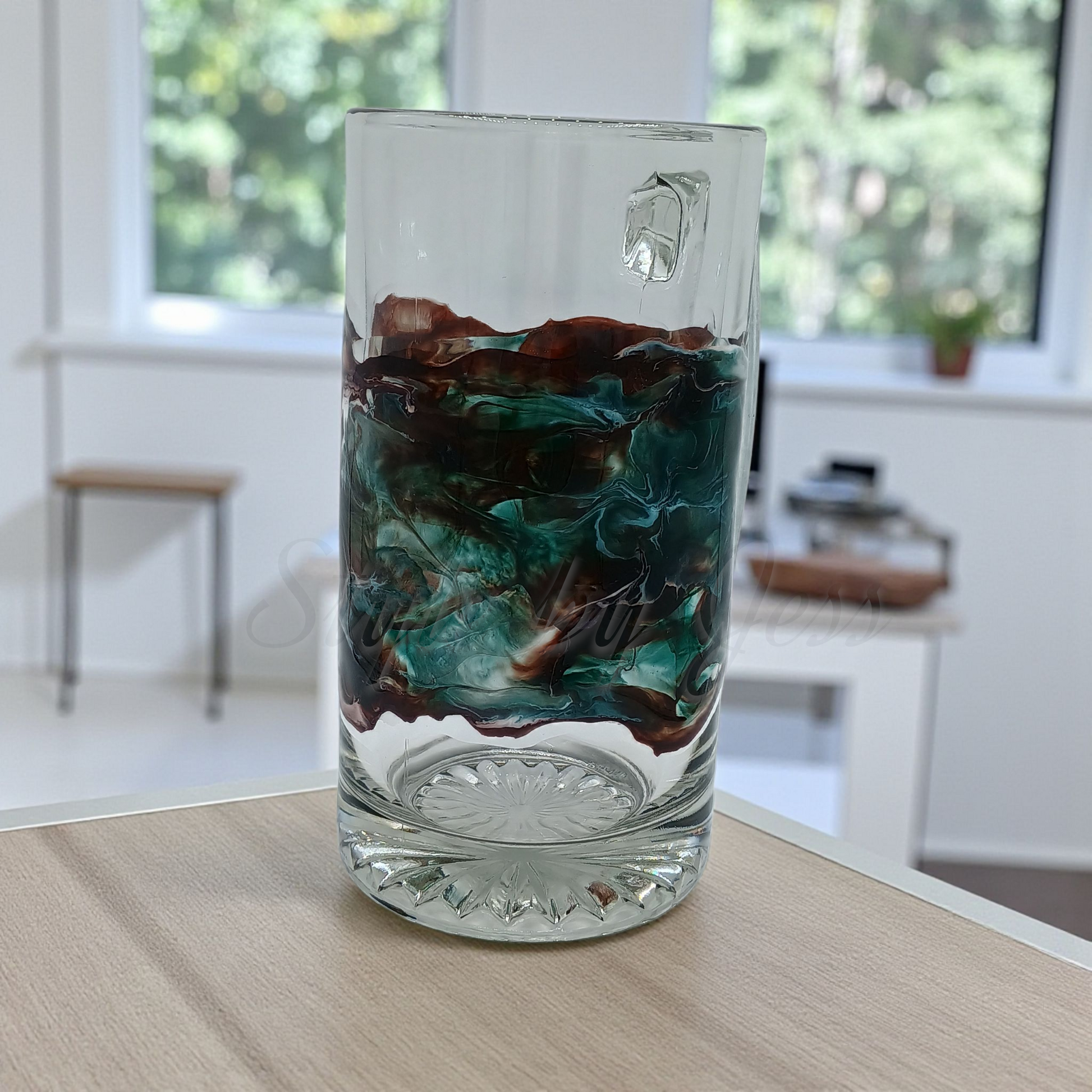 Custom resin art design on a glass mug on a wooden surface